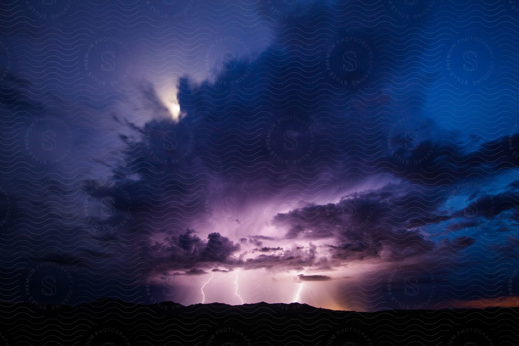 A thunderstorm over the chiricahua mountains creates three lightning bolts with the moon providing beautiful backlight