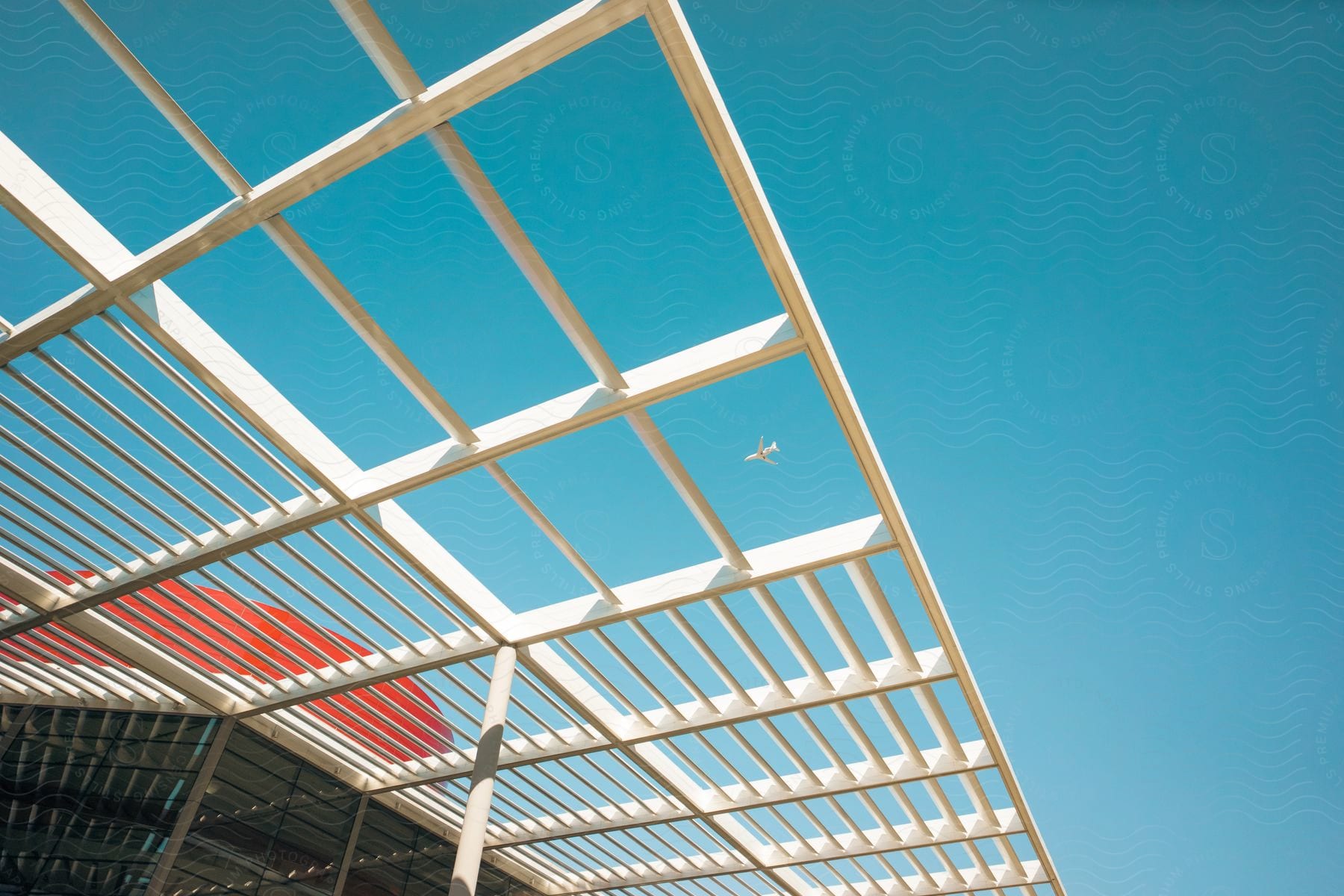 A small plane flies over a large building in daylight