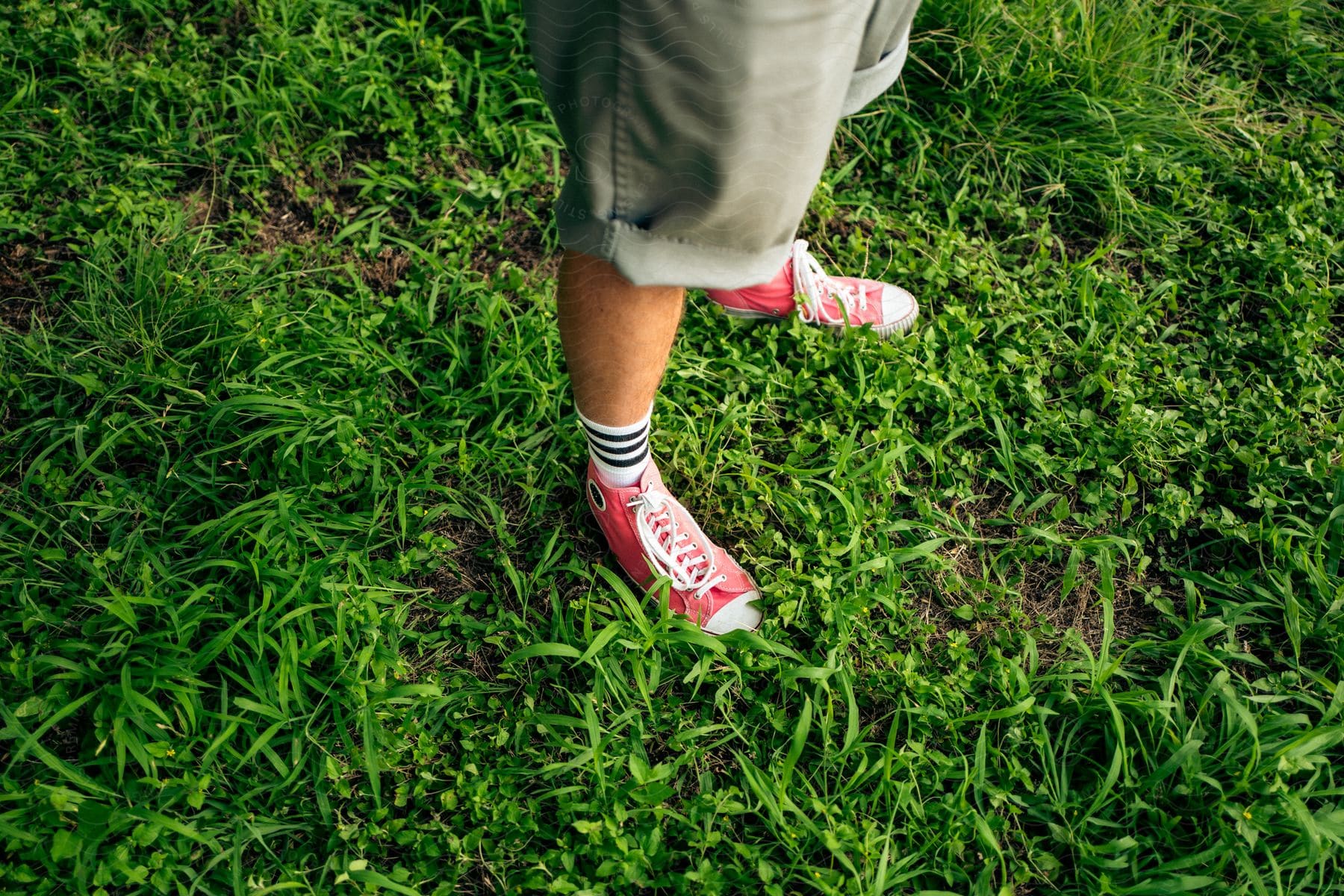 A person walking on grass wearing shorts and sneakers