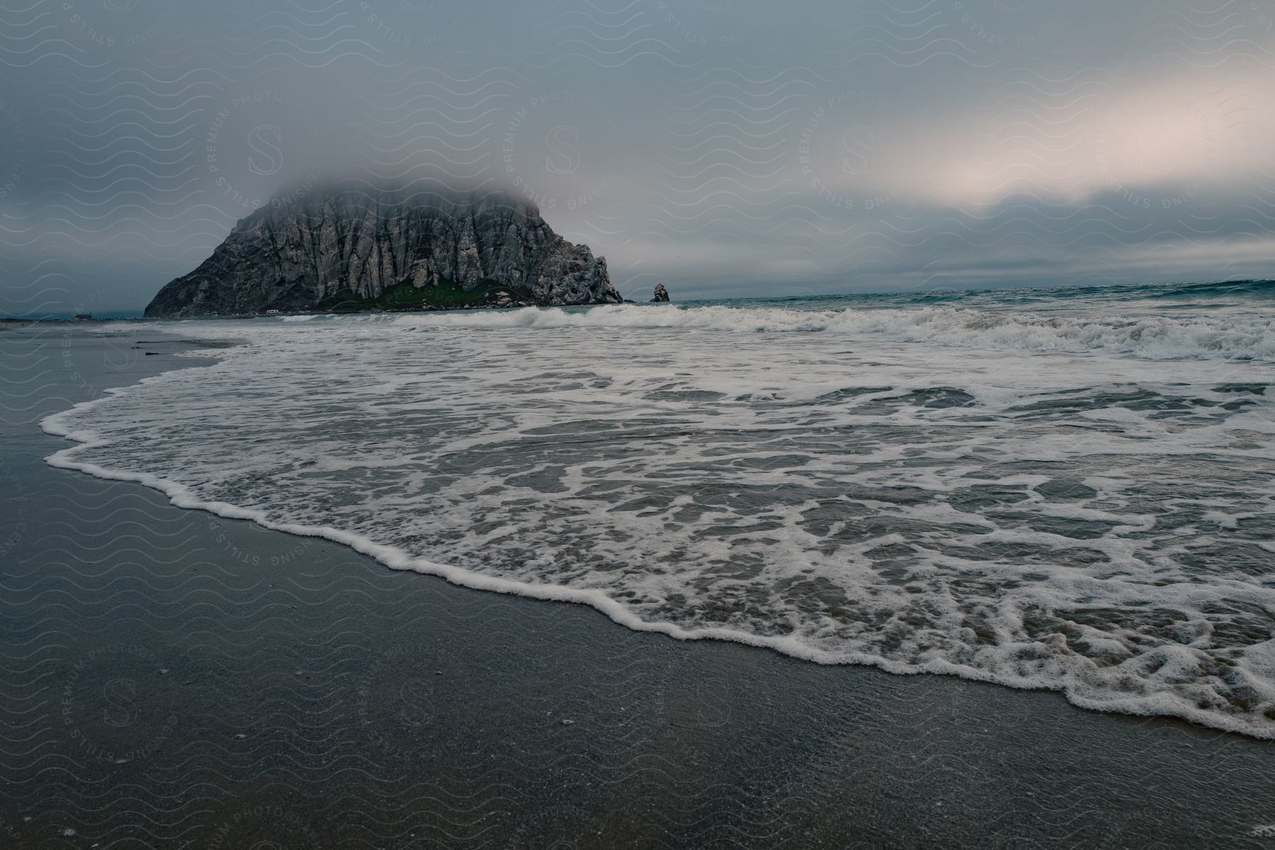 A fogcovered beach with a large rock