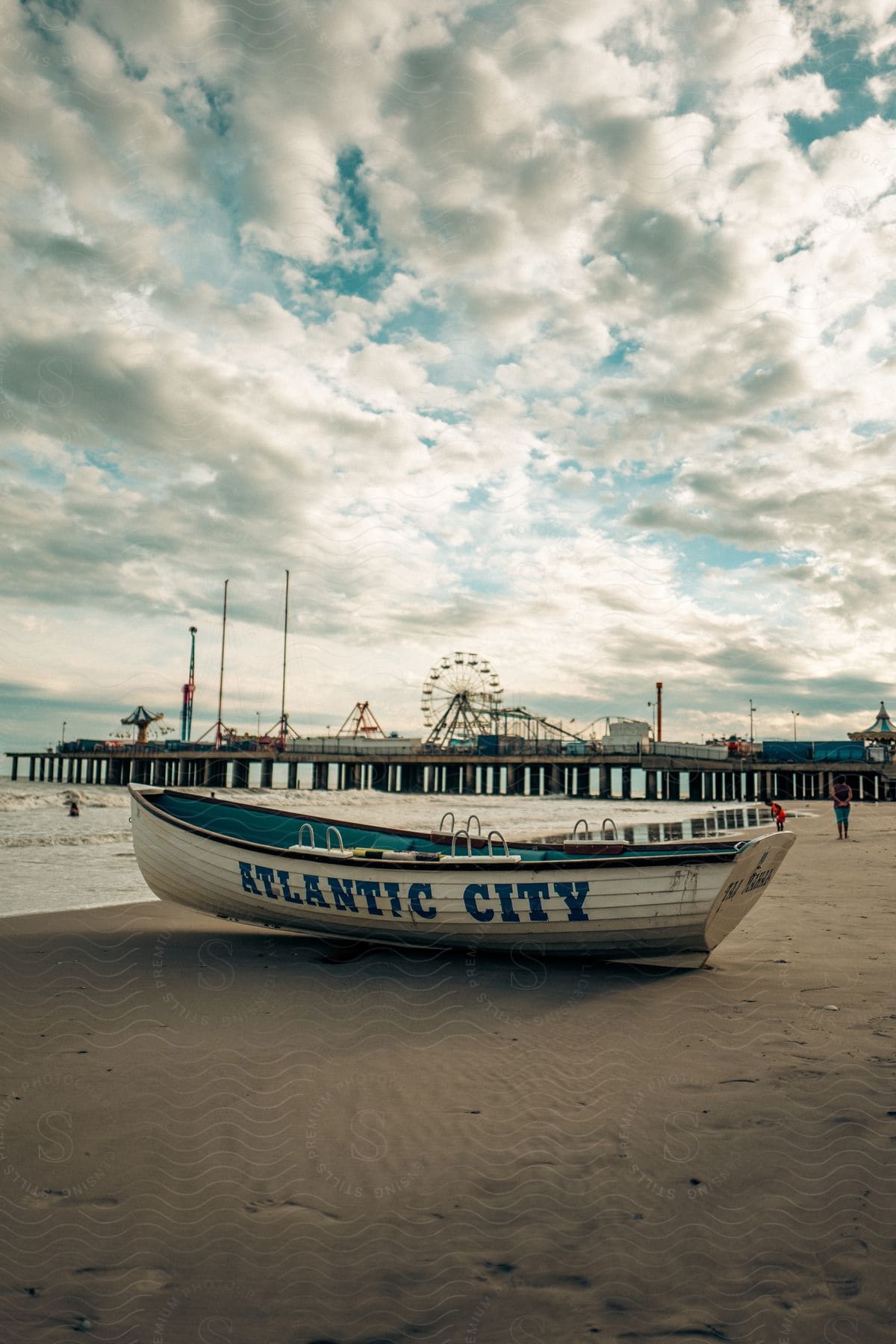 Rowboat with atlantic city inscription on shore under cloudy skies with iconic atlantic city theme park pier in background