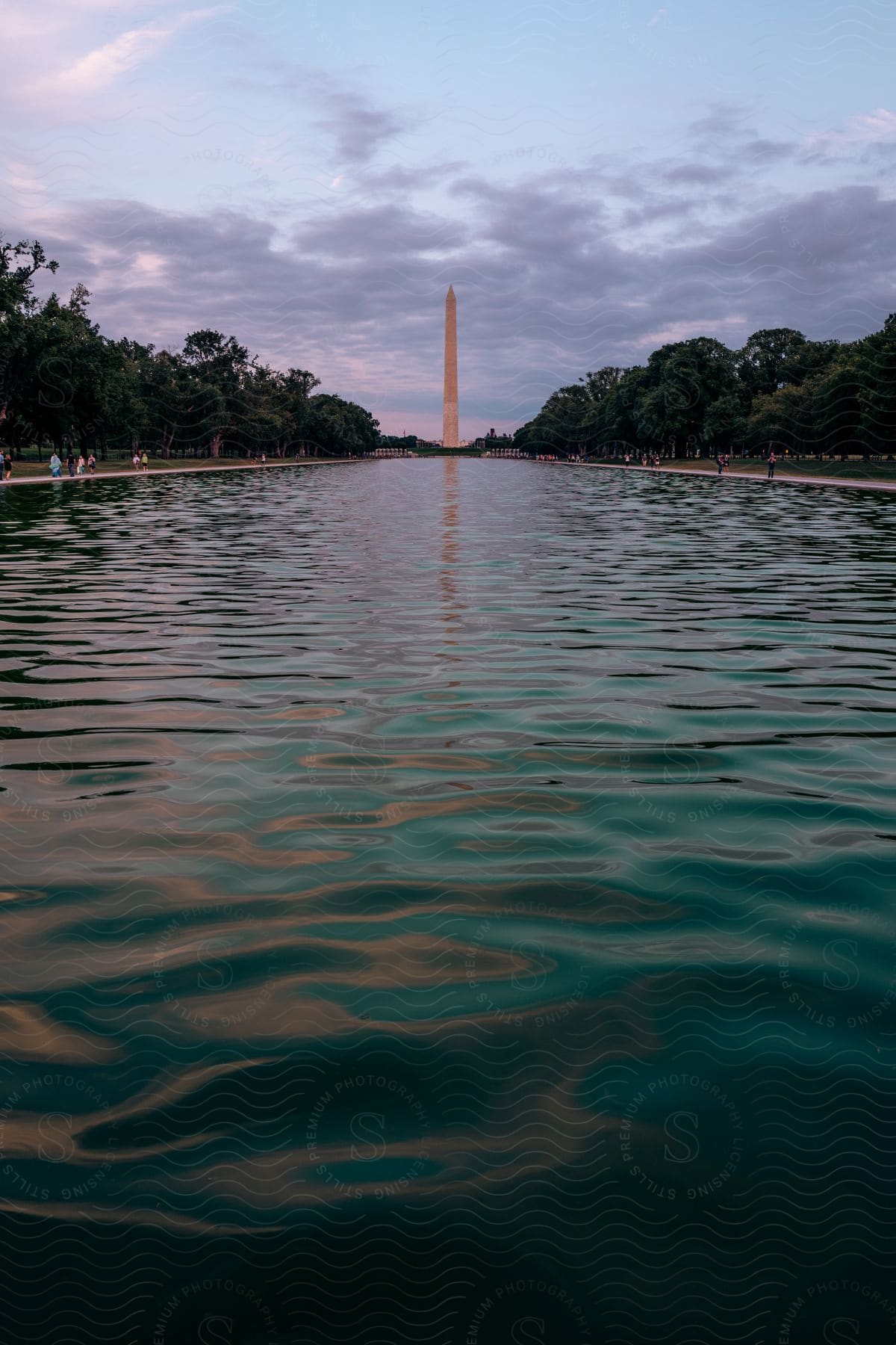 The washington monument in front of the lincoln memorial reflecting pool at evening