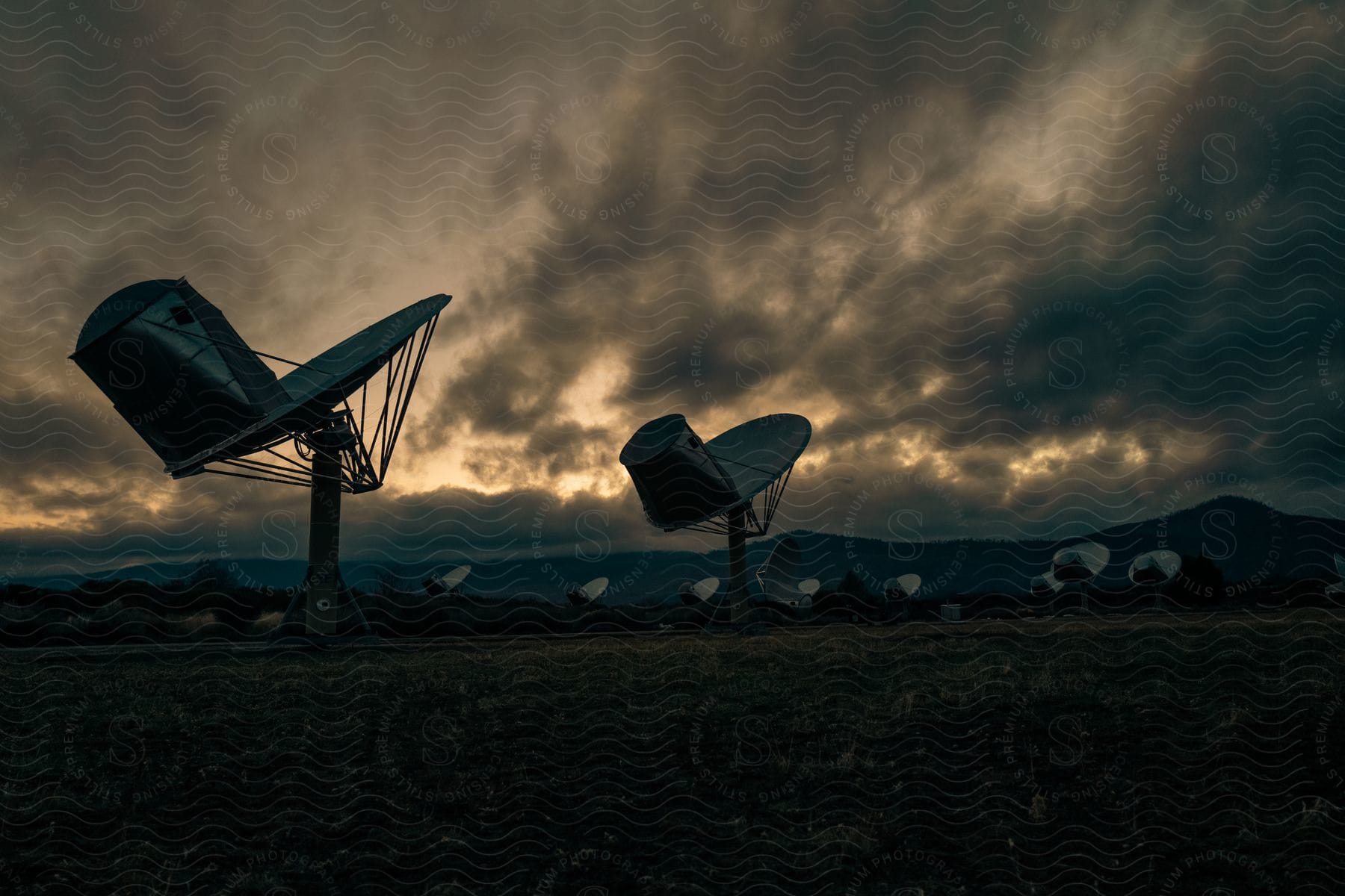 Stock photo of satellite dishes point skyward in a flat field
