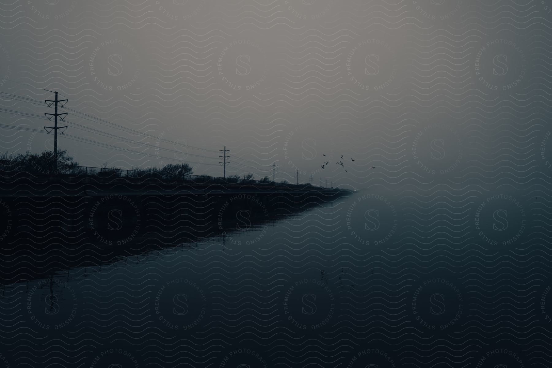 Power lines run along the shore of a lake