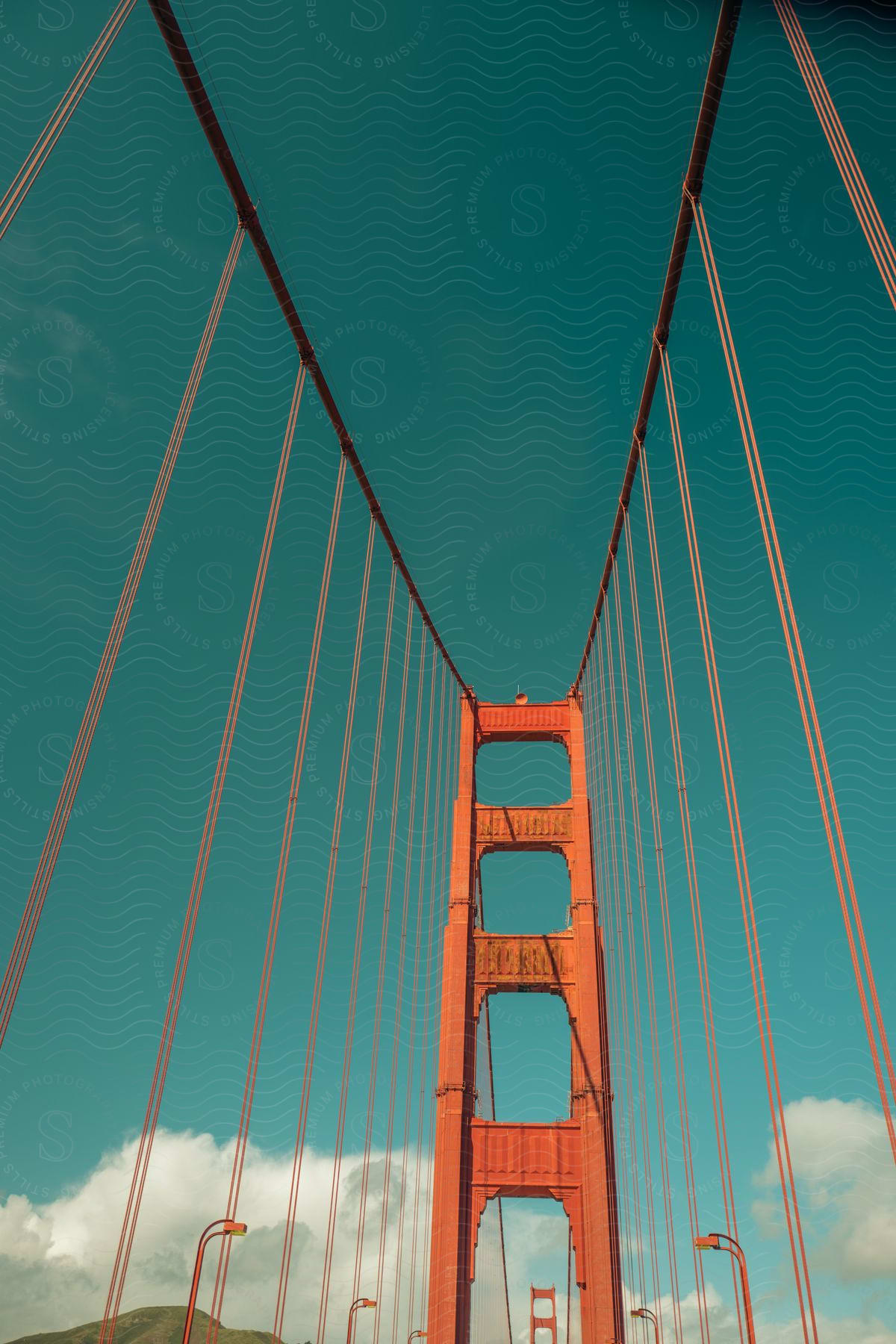 A Suspension Bridge Against An Orange Sky With Clouds