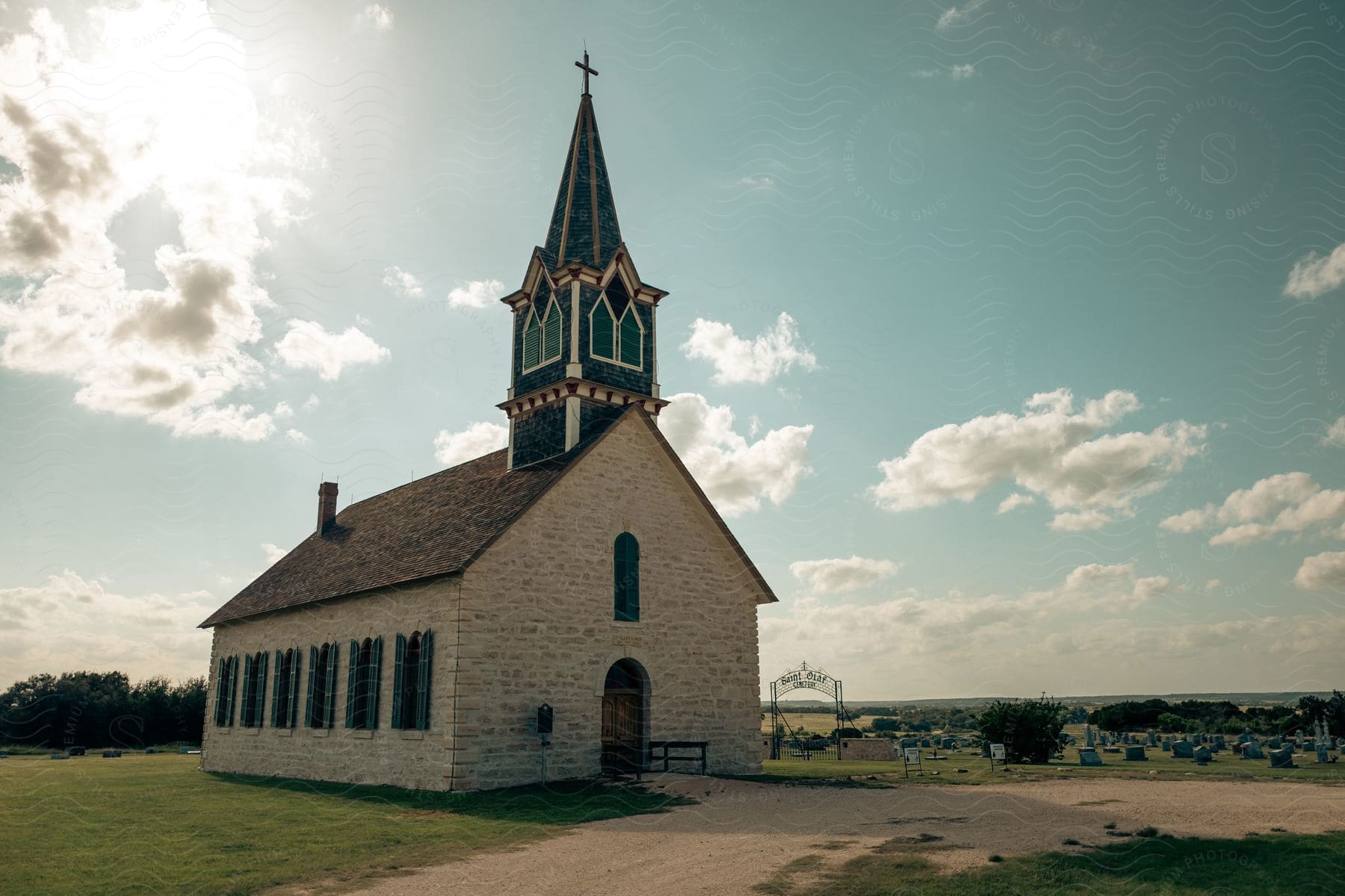 A church with a tall green tower next to a cemetery in a small town