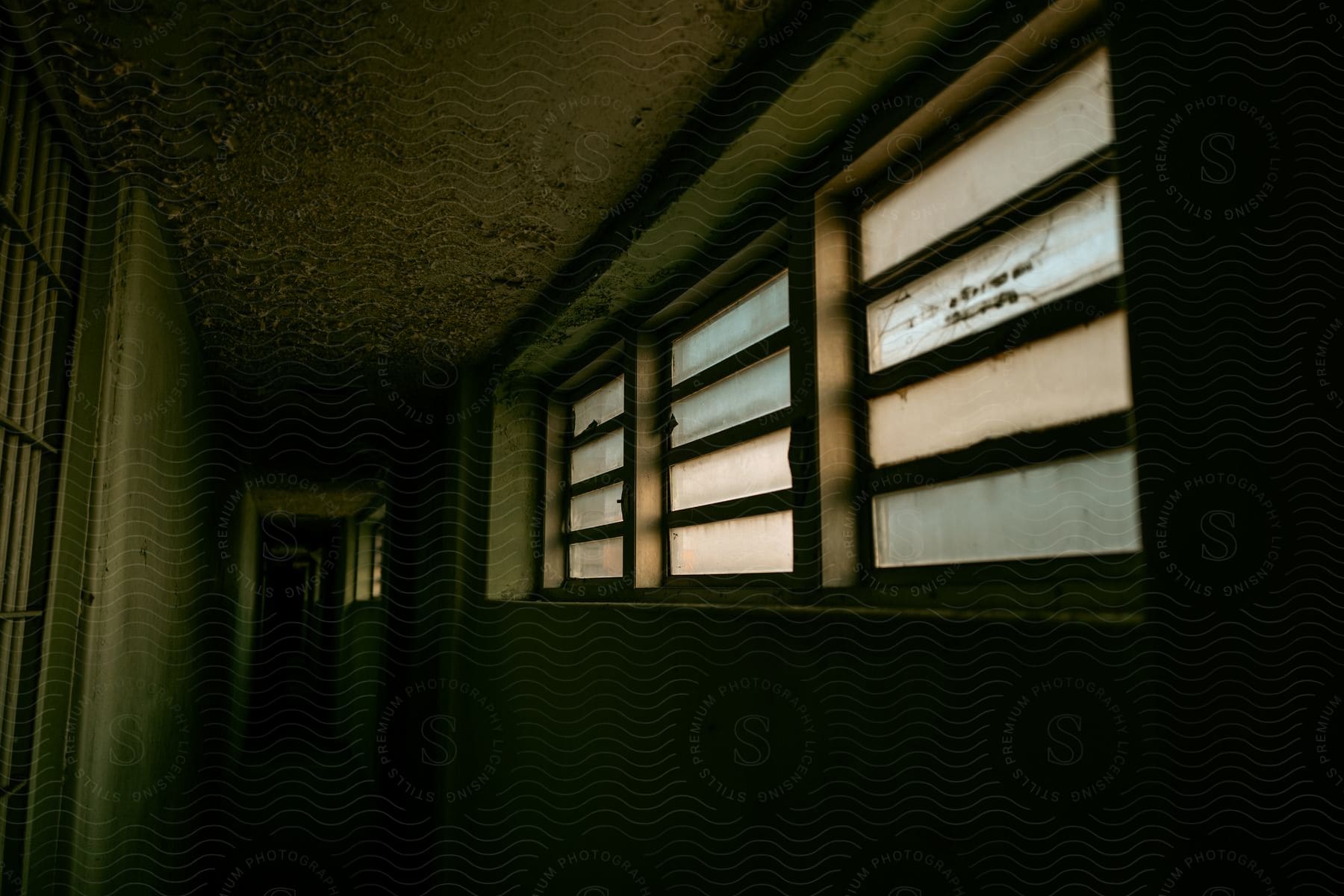 Dark interior of a building with small windows and a dirty environment