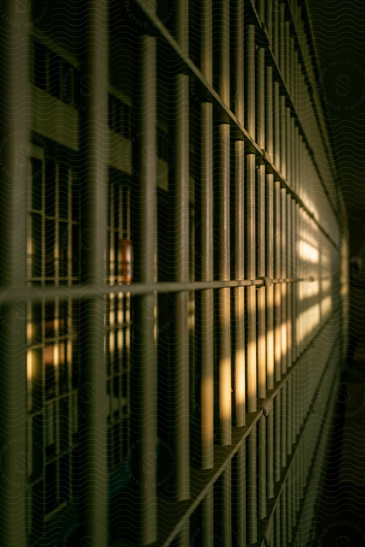 Light shines on bars in a jail corridor in an interior building