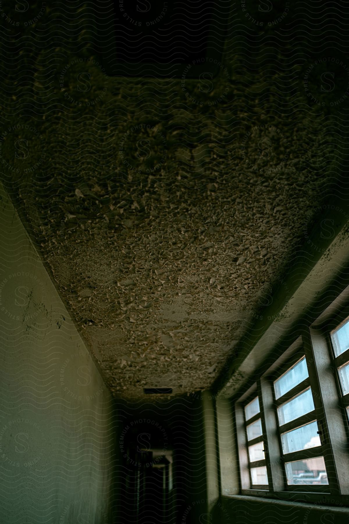 Corridor with worn and broken ceiling in room