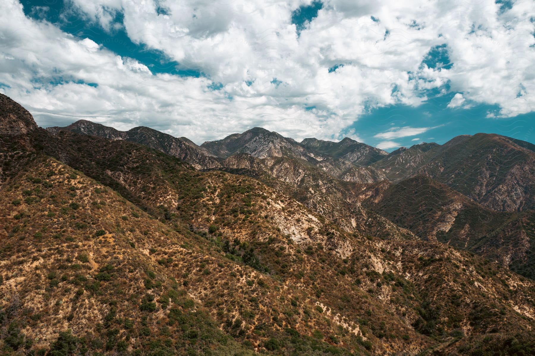 A partly cloudy sky hangs over a slightly barren mountain range