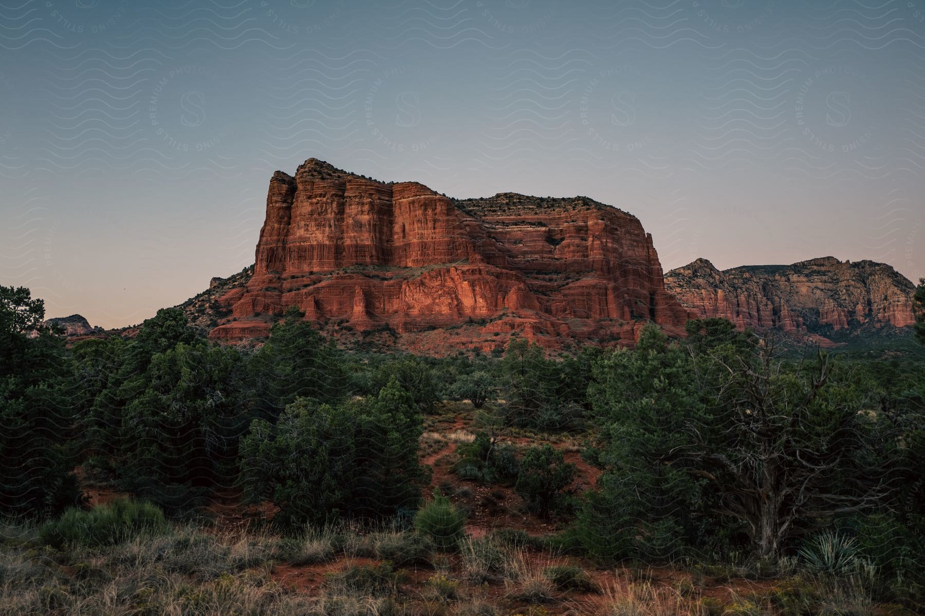 A serene natural landscape with mountains trees rocks and a clear sky