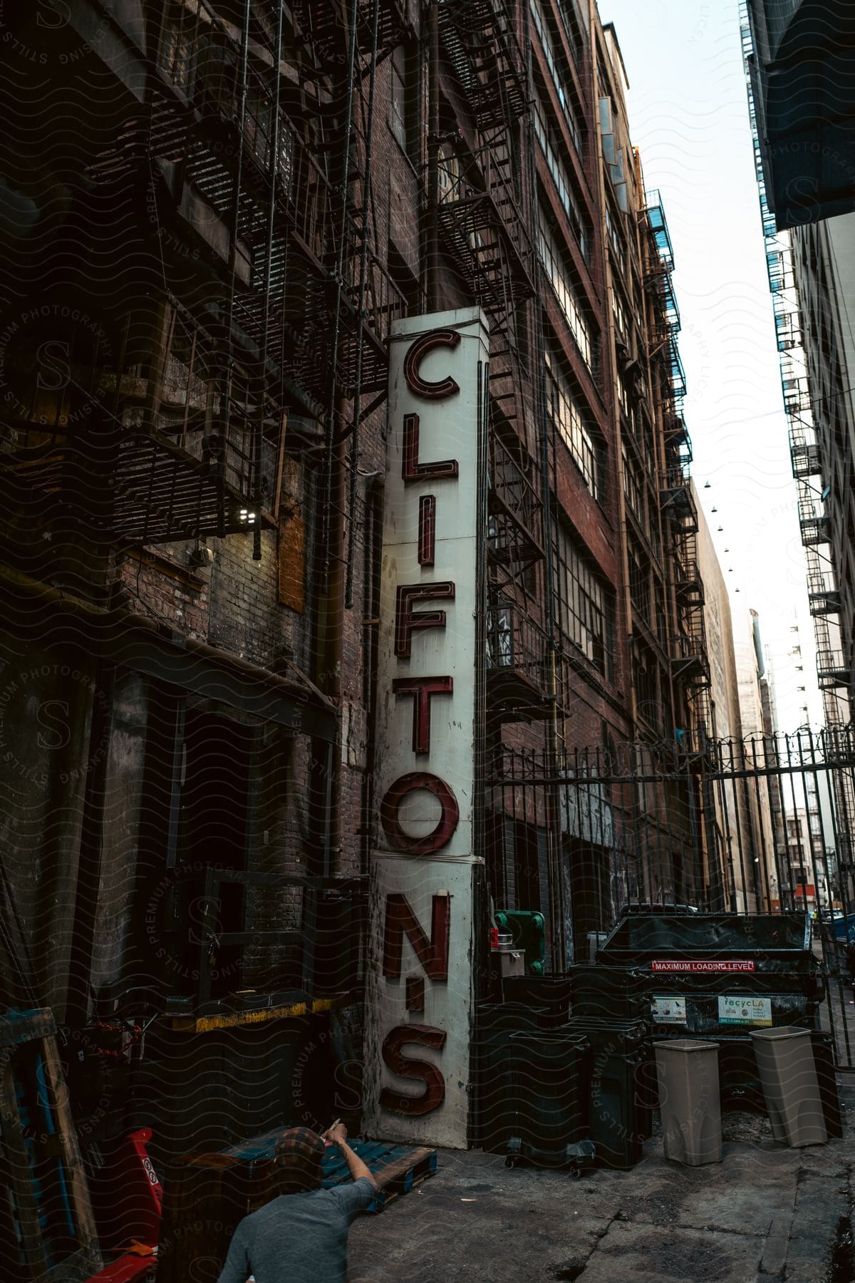 A man gestures towards a sign by city buildings