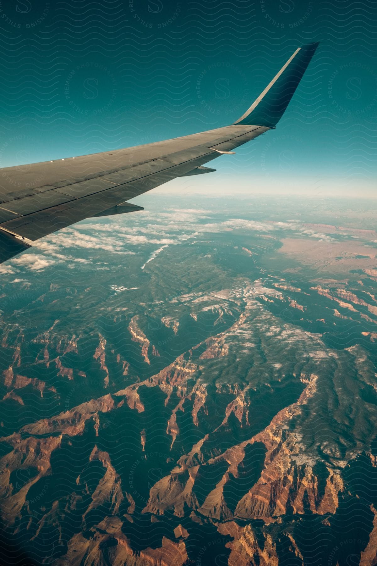 A mountain range is seen with a plane wing in the foreground