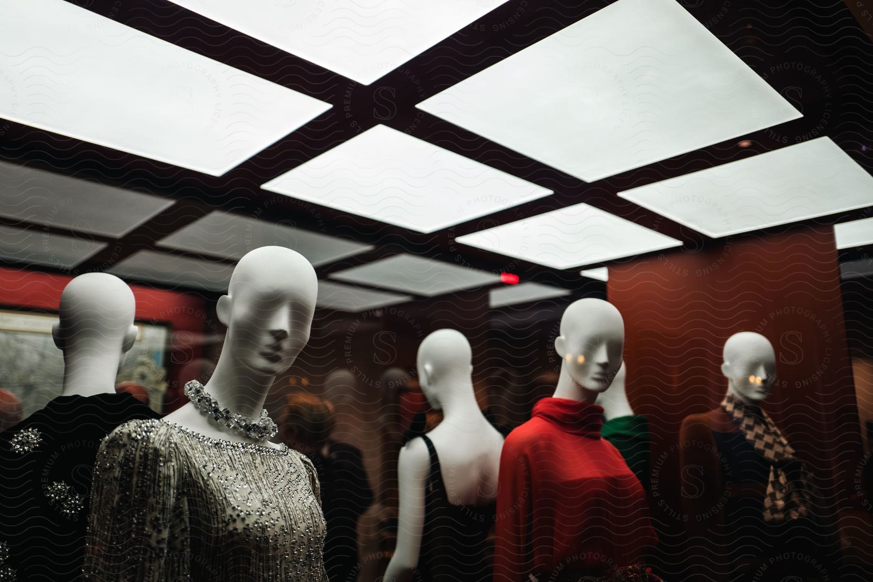 Mannequins with womens clothes lined up behind a window under bright lights