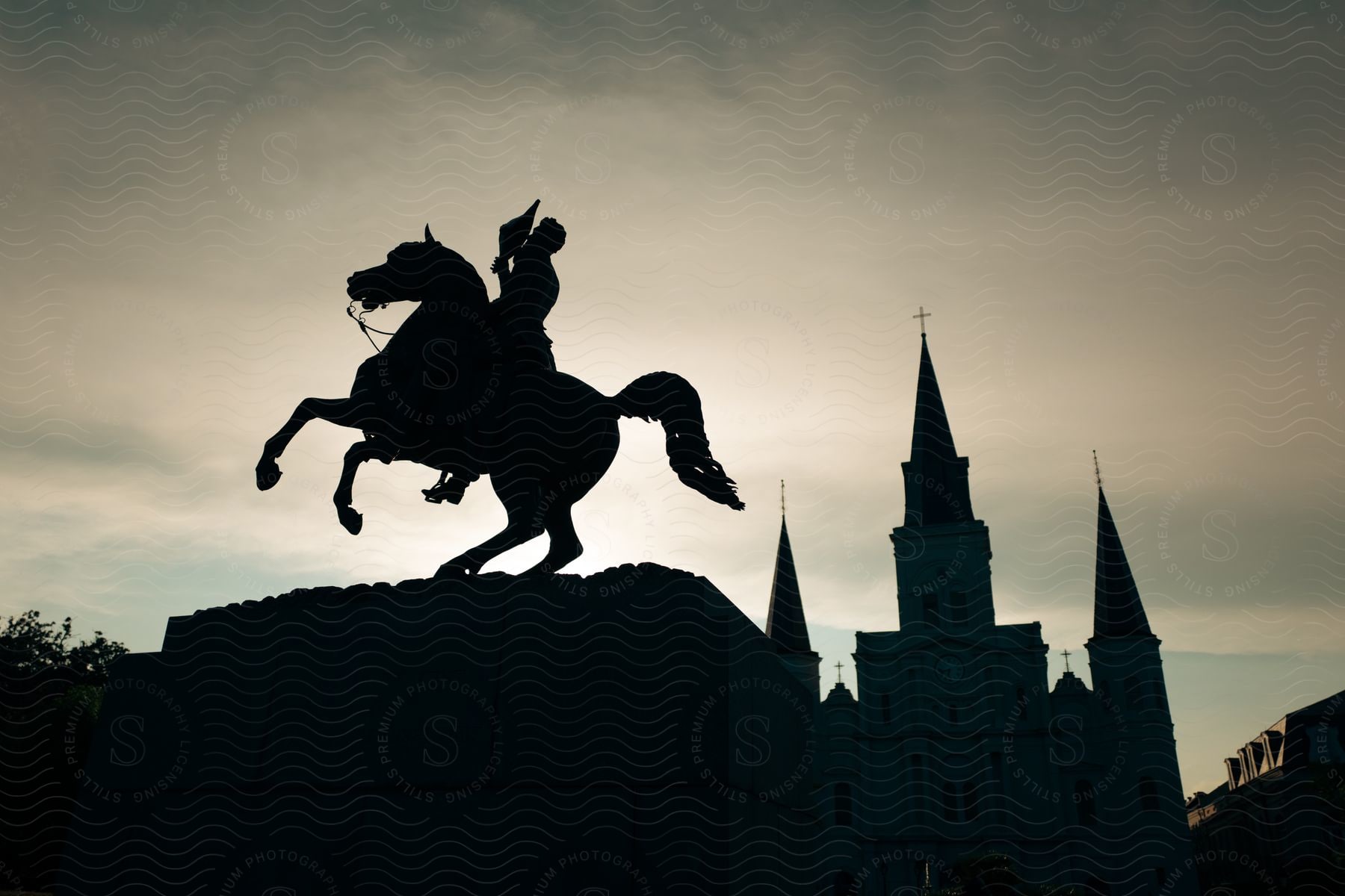 Statue of a horse and soldier on a monument with a church against a cloudy sky