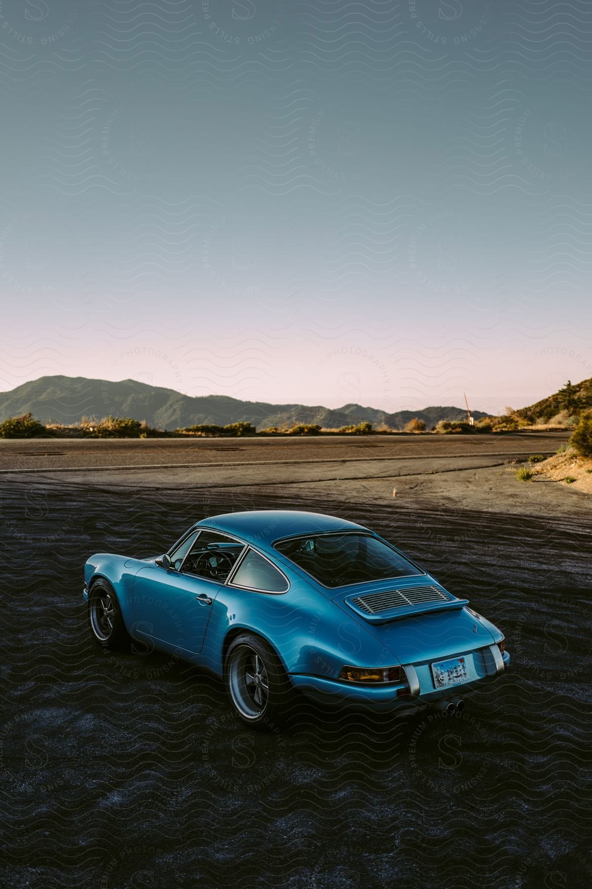 A metallic blue classic vintage porsche parked in the shade of the desert