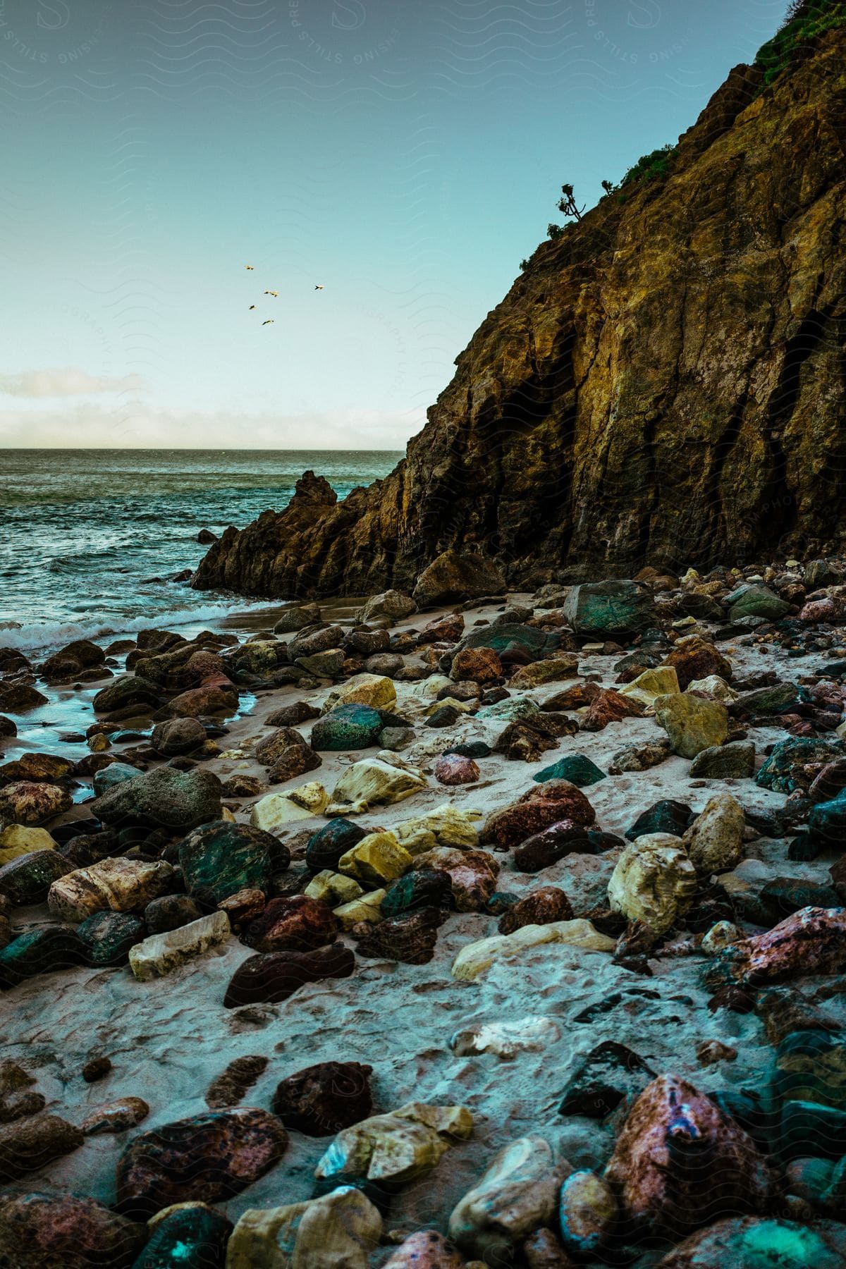 A serene coastal landscape with rocks and a pebble beach