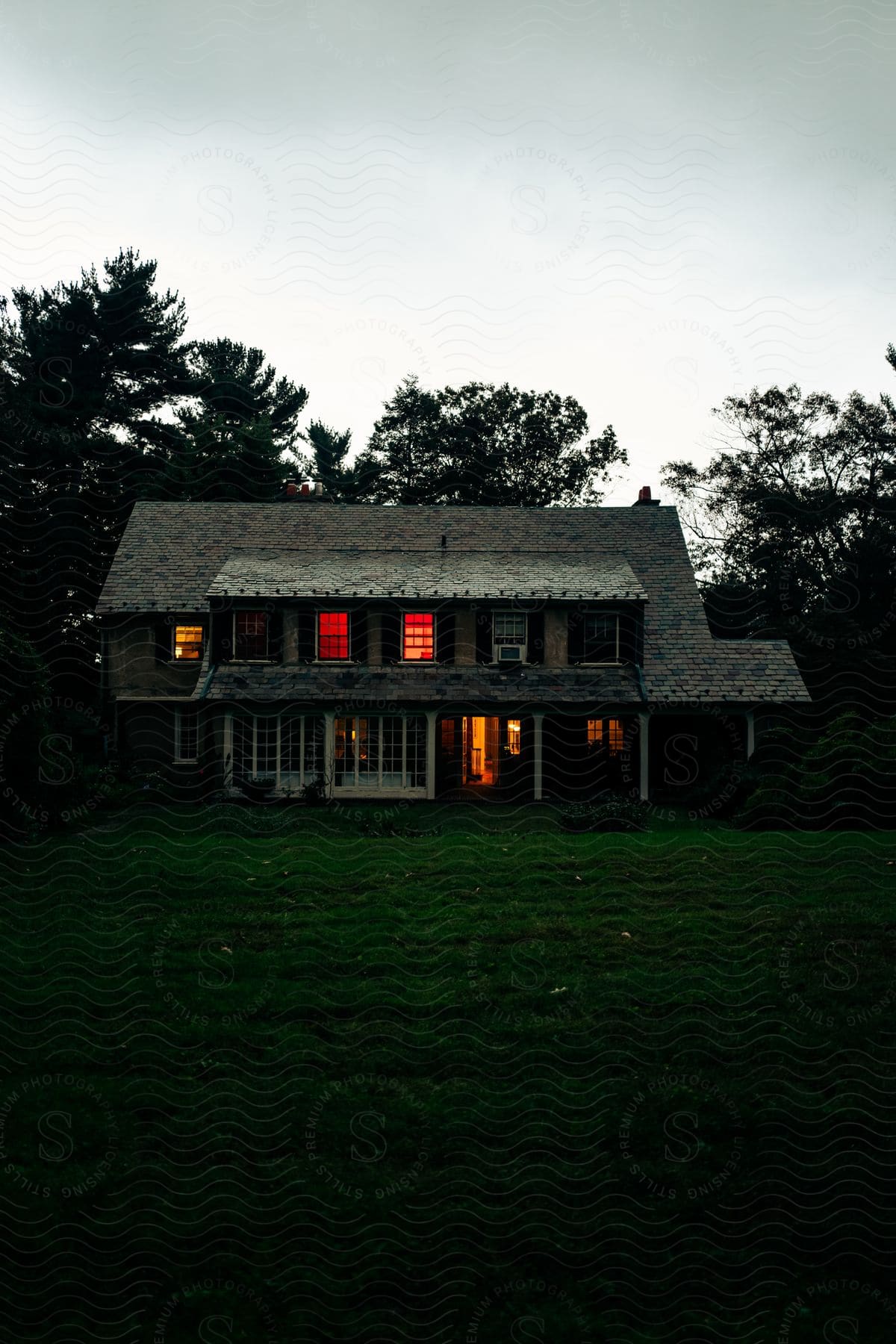 A lit up house at dusk in a neighborhood