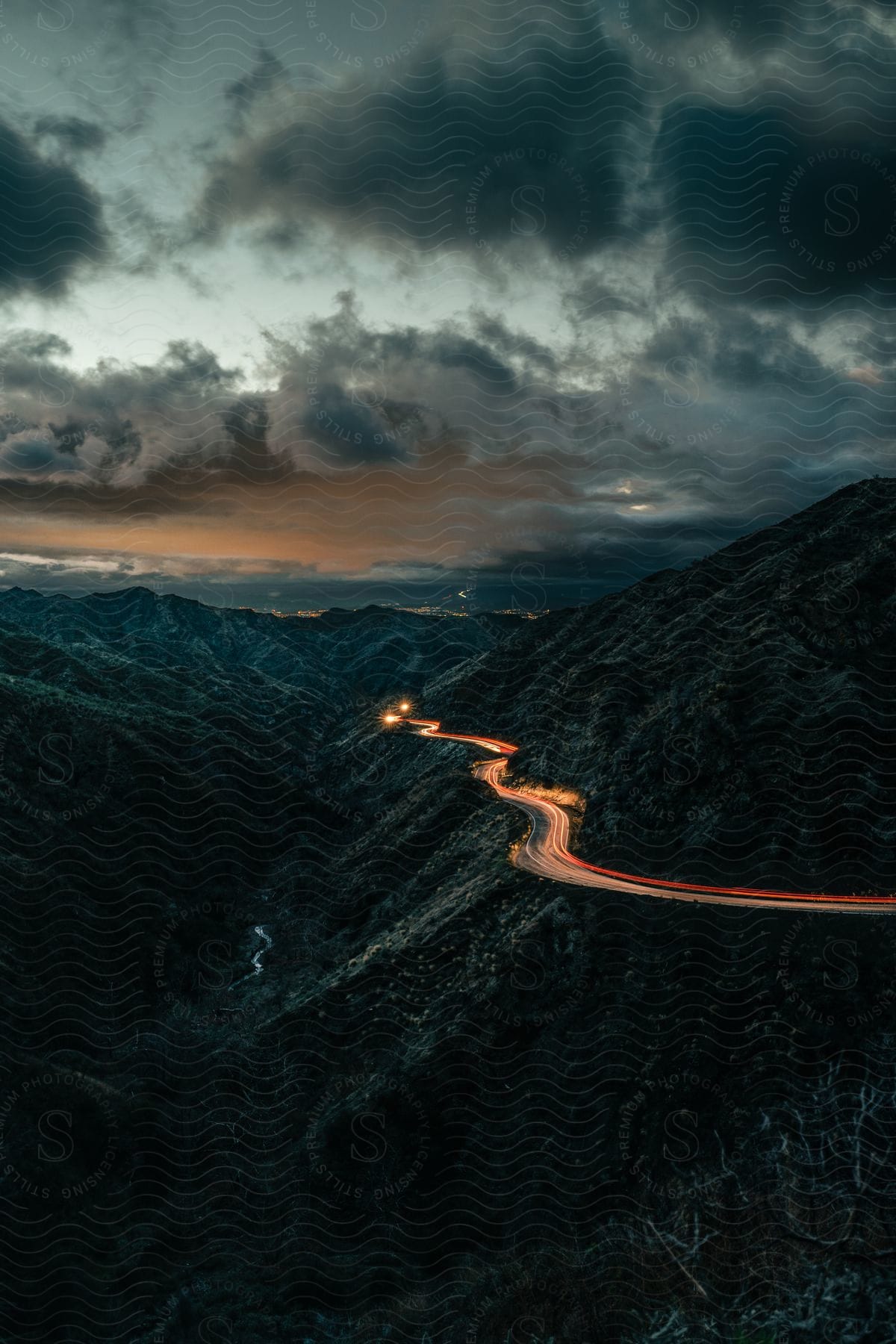 Aerial view of a mountainous natural landscape with a road and cloudy sky