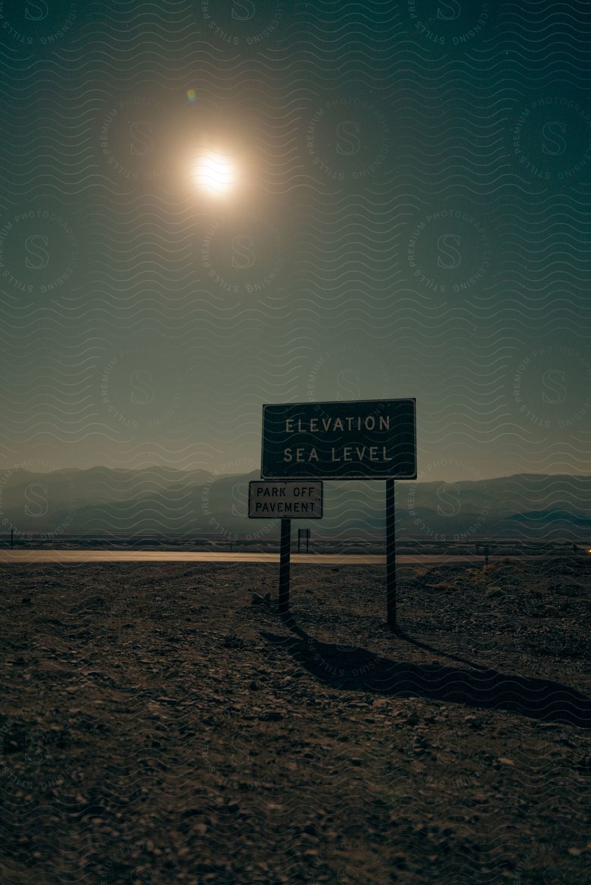 Road signs on a road next to a mountain range