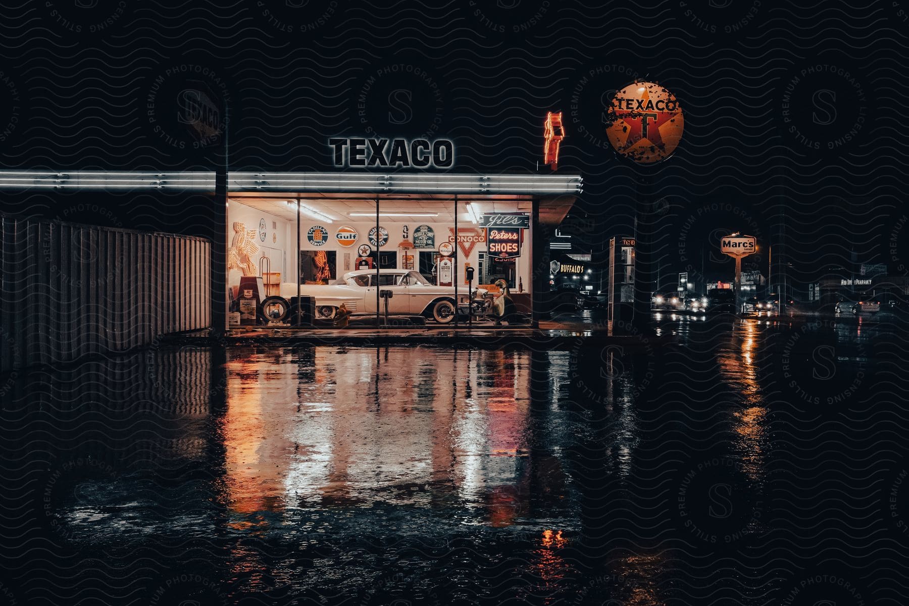 A Lit Up Texaco With A Vintage White Car Inside Against A Dark Night Sky