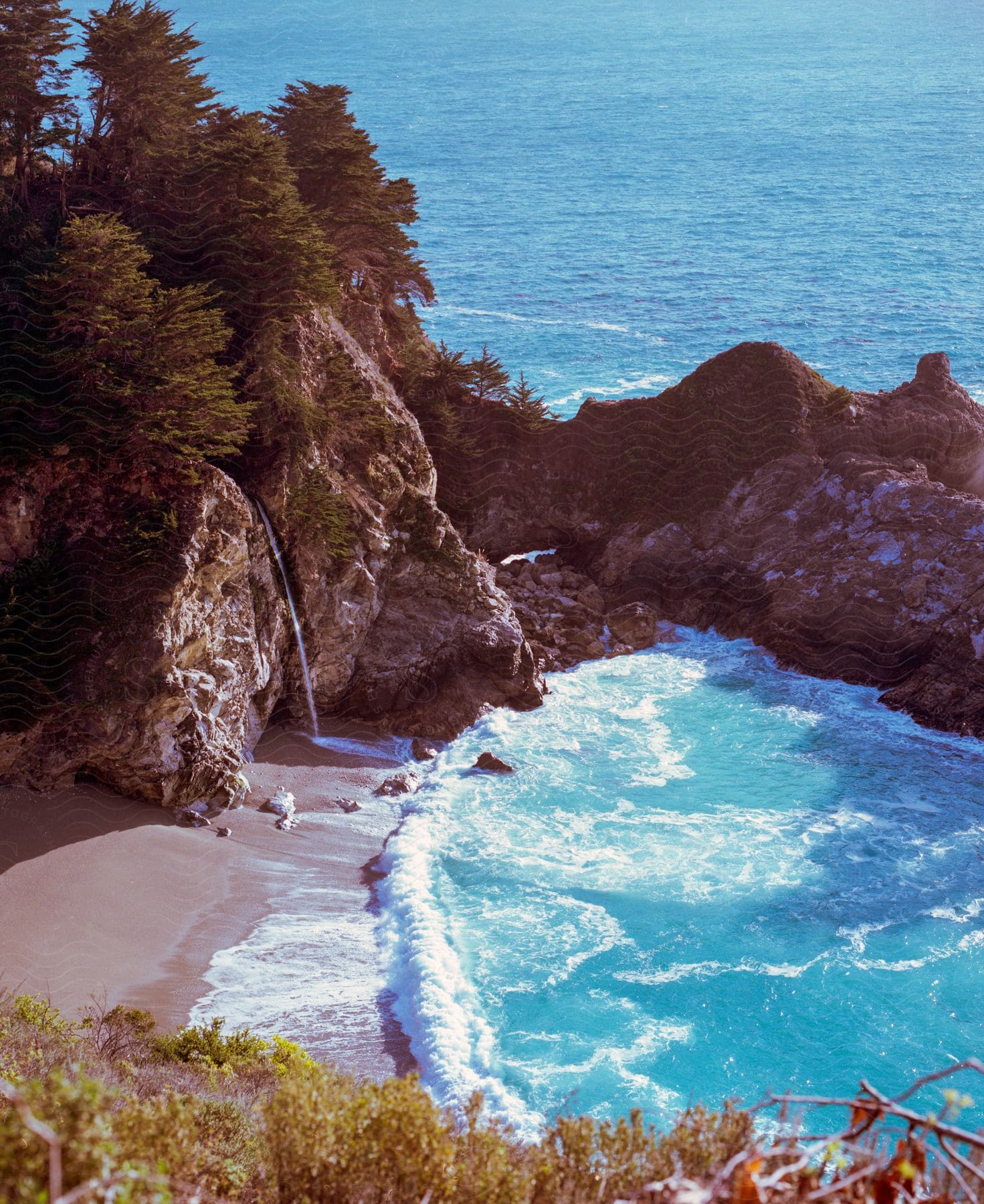 A tranquil coastal landscape with rocks trees and a beach