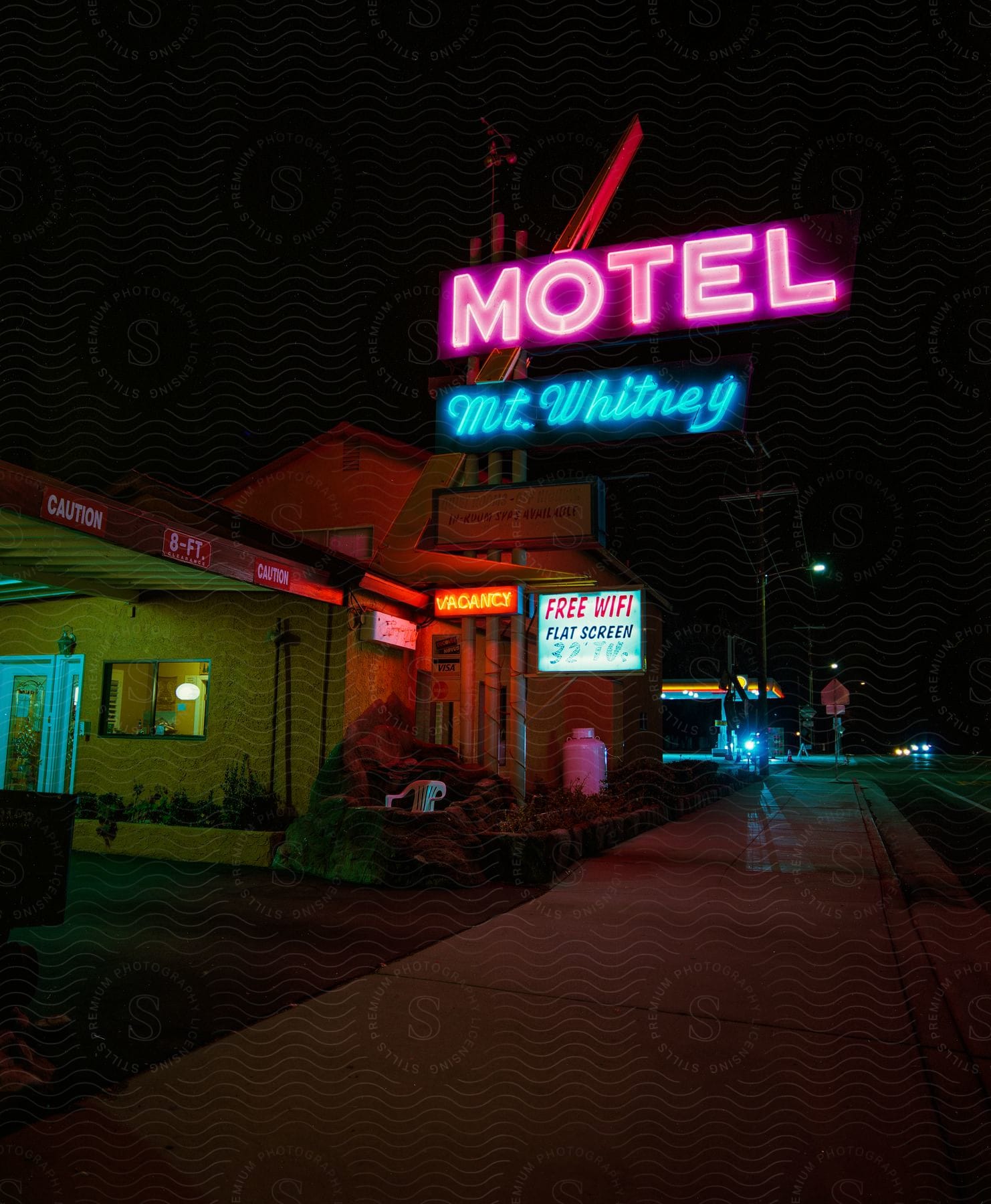 Exterior of motel building and sign next to highway at night