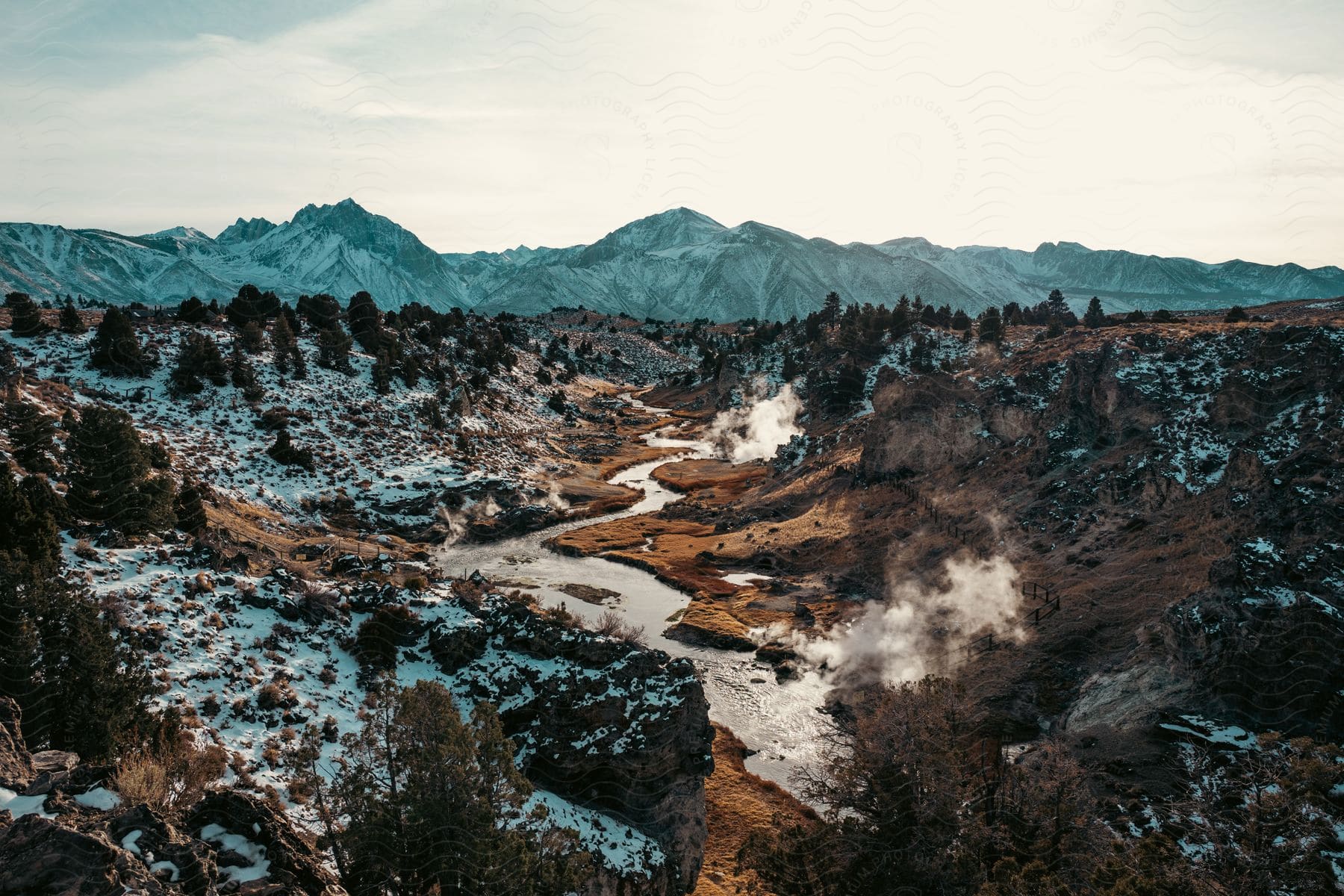 Landscape of hot creek and snowy mountain range in the background