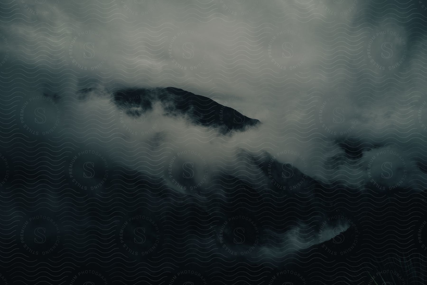 A cloudy sky with smoke in the air over a mountainous landscape