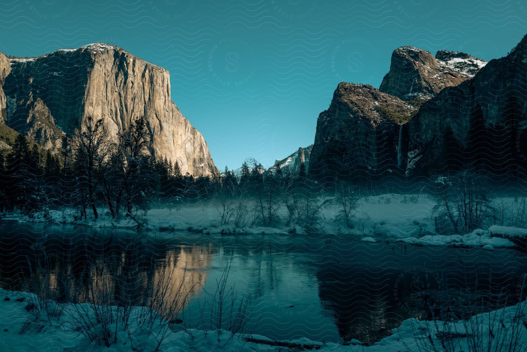 A partially frozen lake is framed by two mountain cliffs