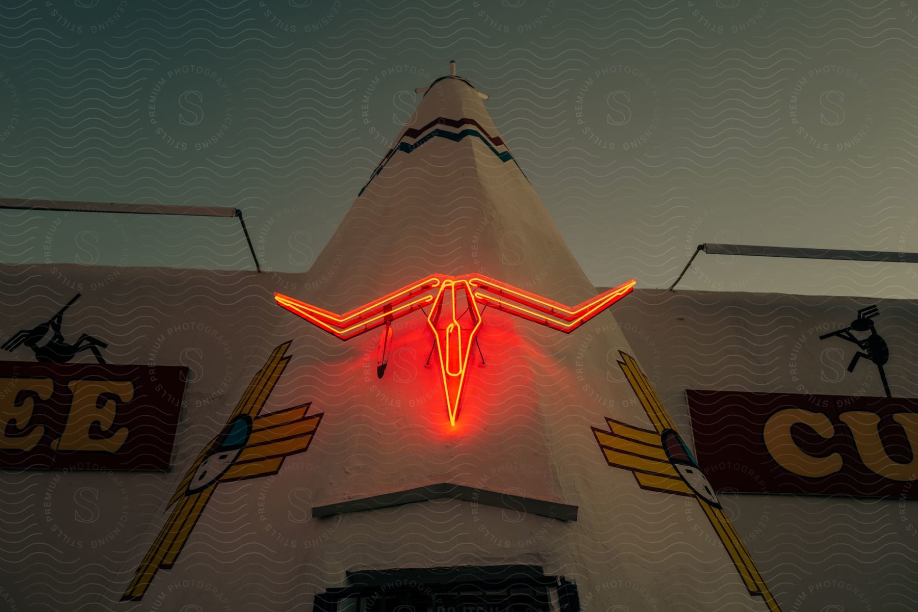 Exterior of motel with neon cow skull above the door at dusk or dawn