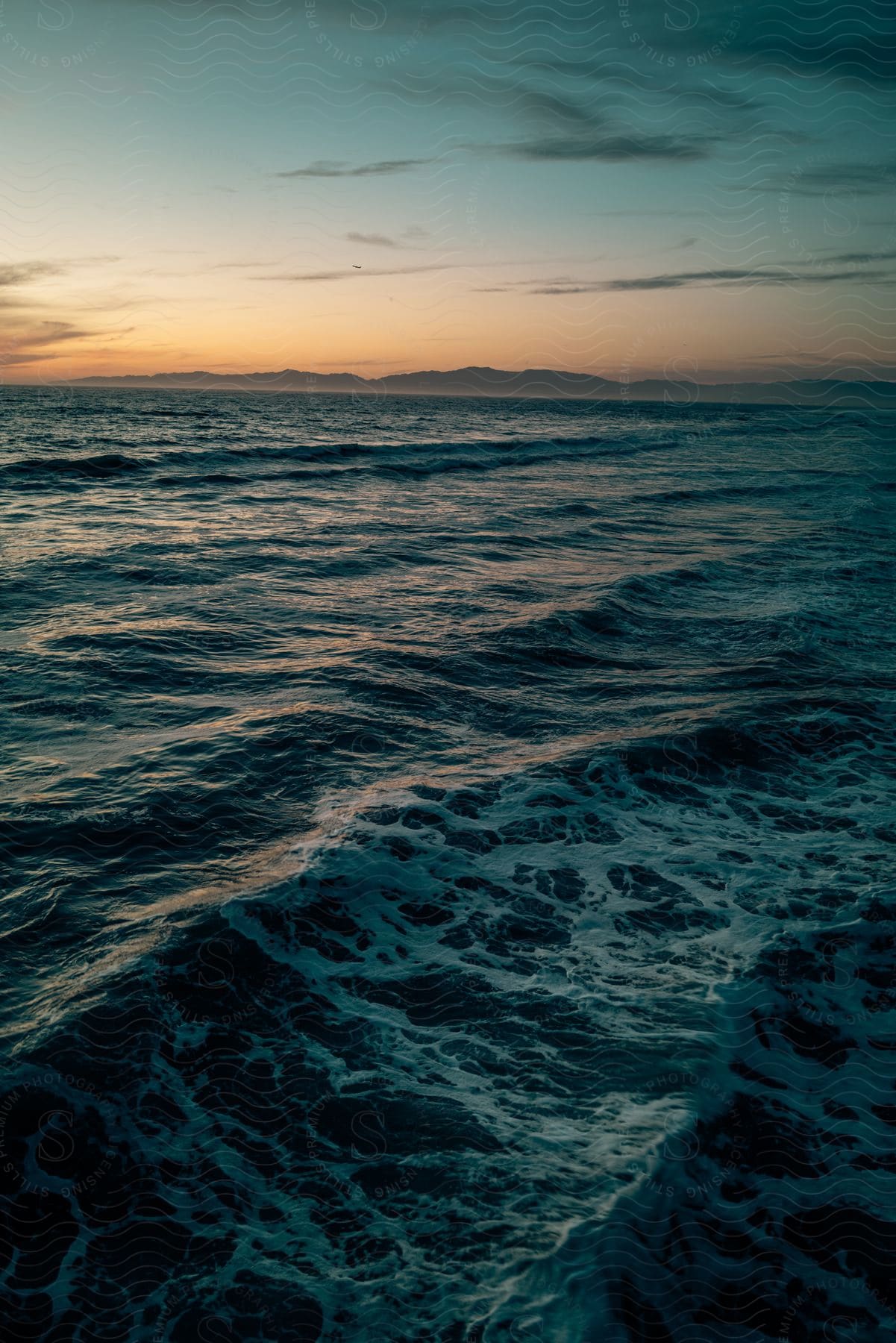 Ocean waves with distant mountains in the horizon at evening