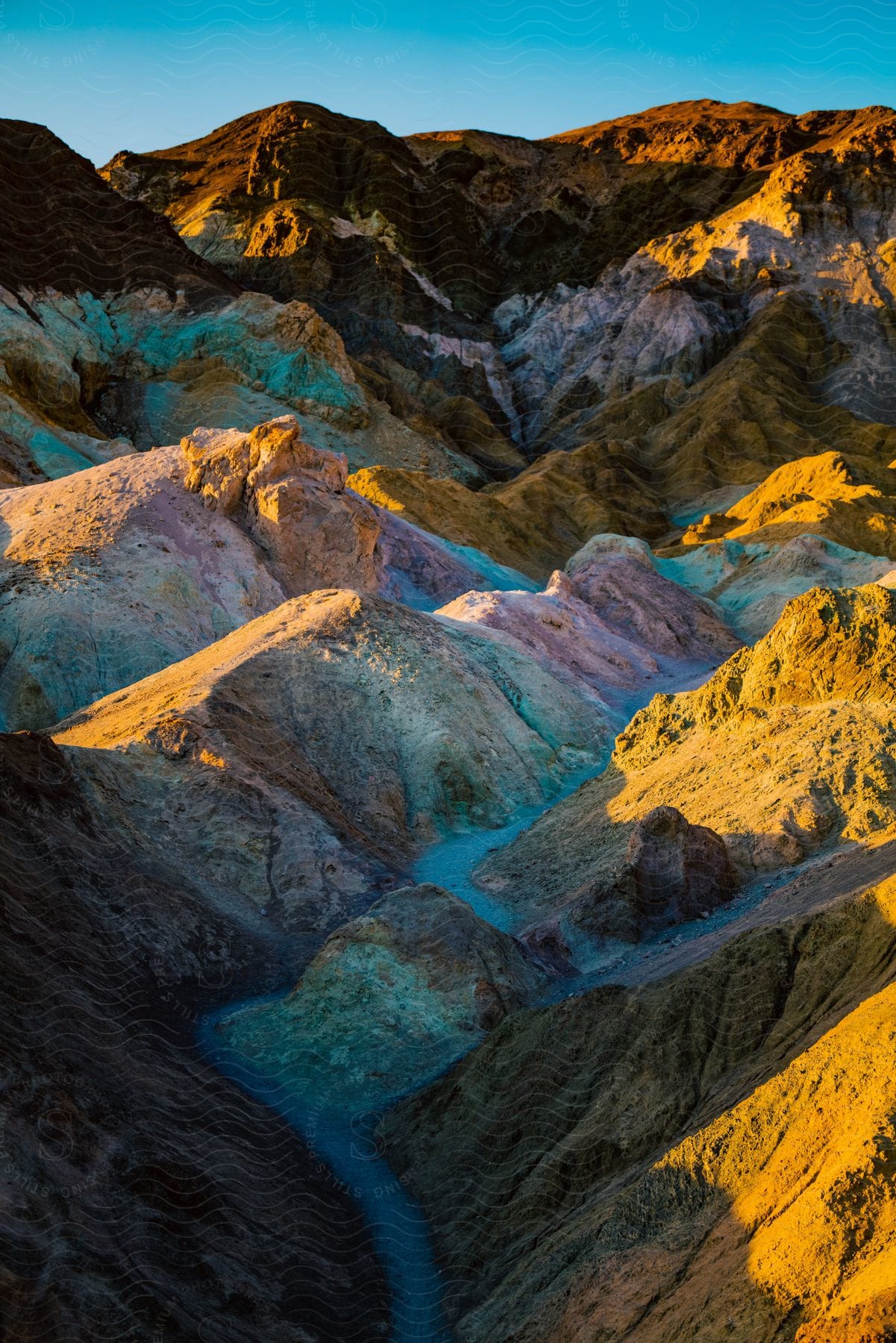 A serene mountain landscape with a clear blue sky and watercourse