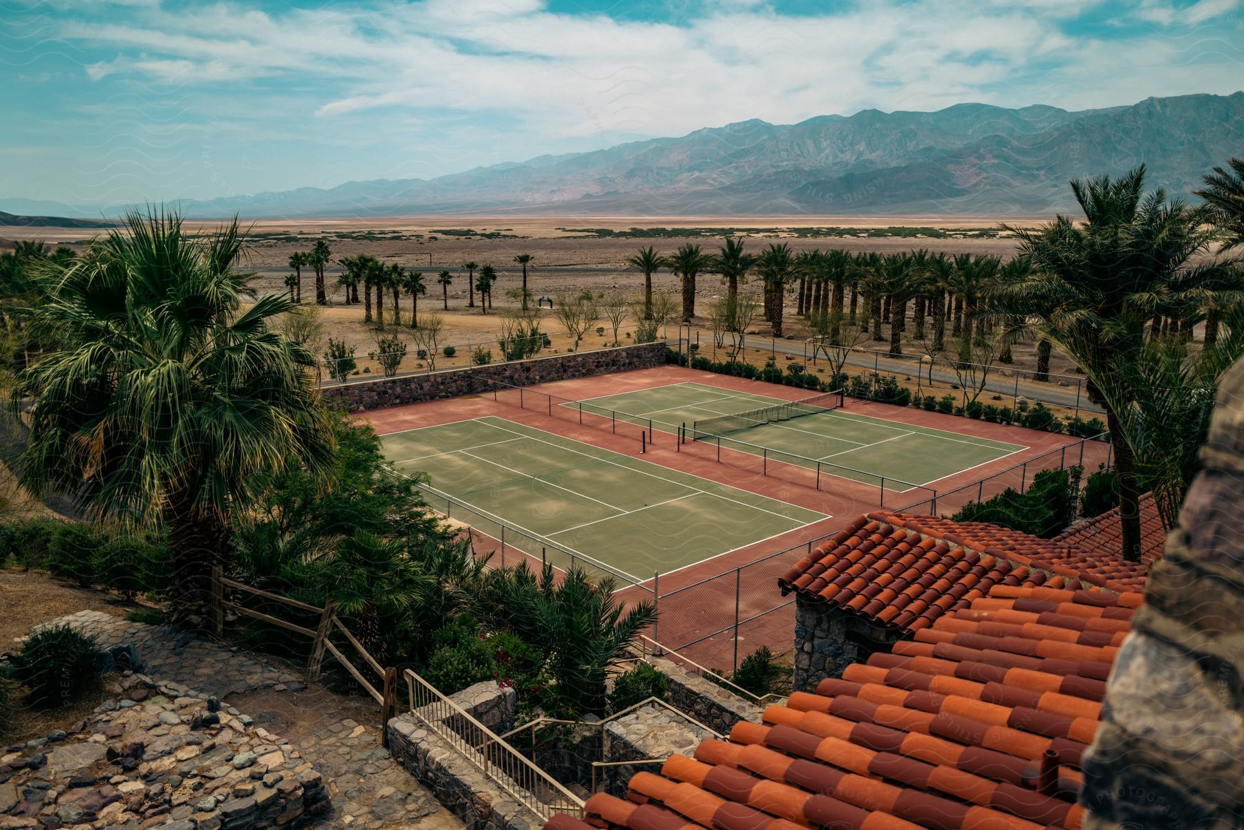 A tennis court with palm trees near a mountain
