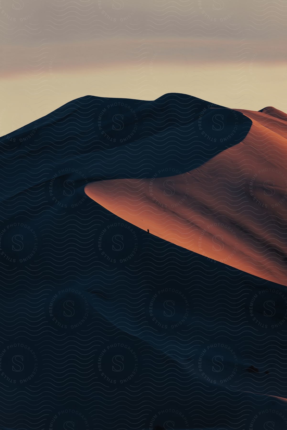 A sand dune rises into the sky at dusk