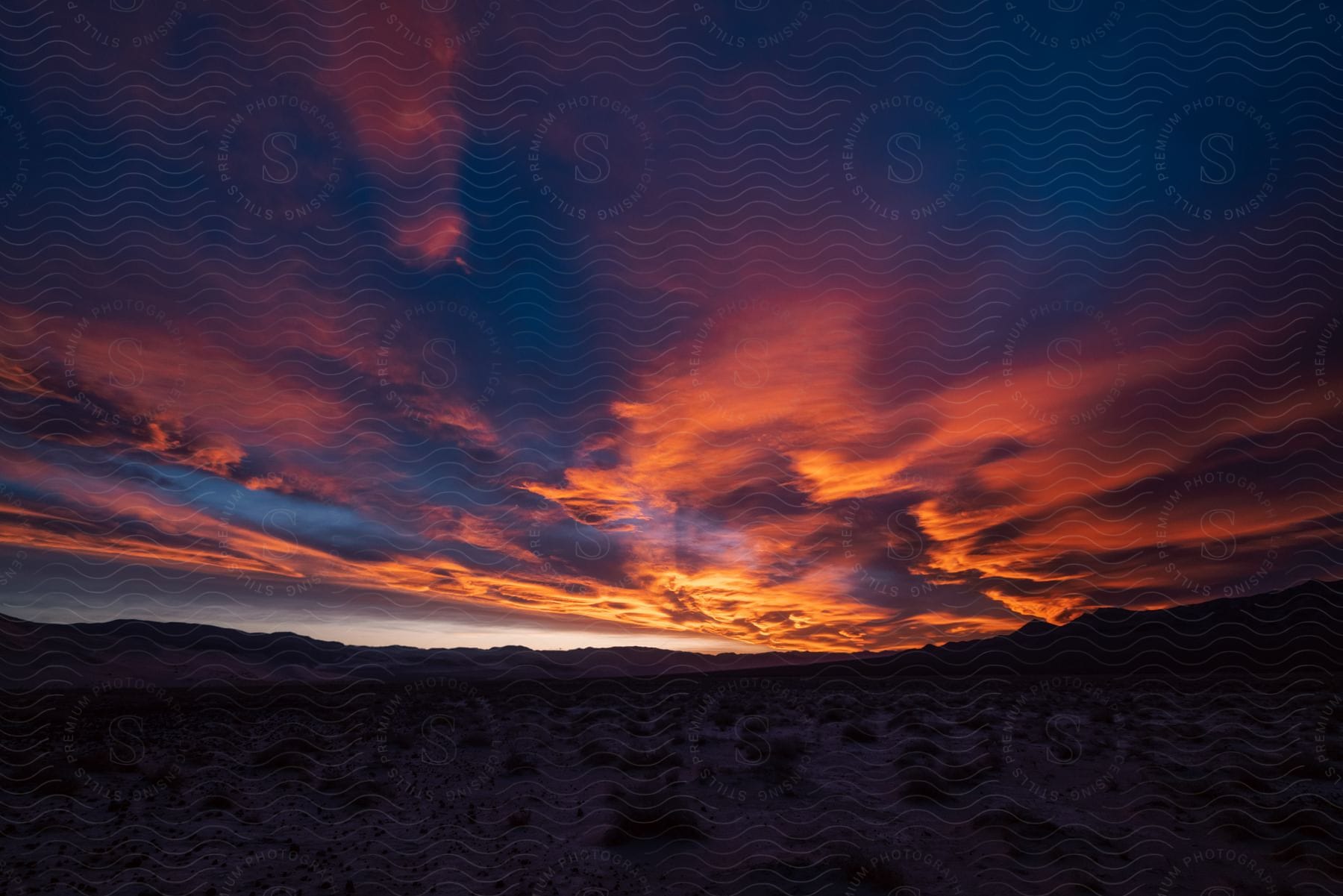 A Silhouette Of Arid Land Against A Red Sky At Sunset