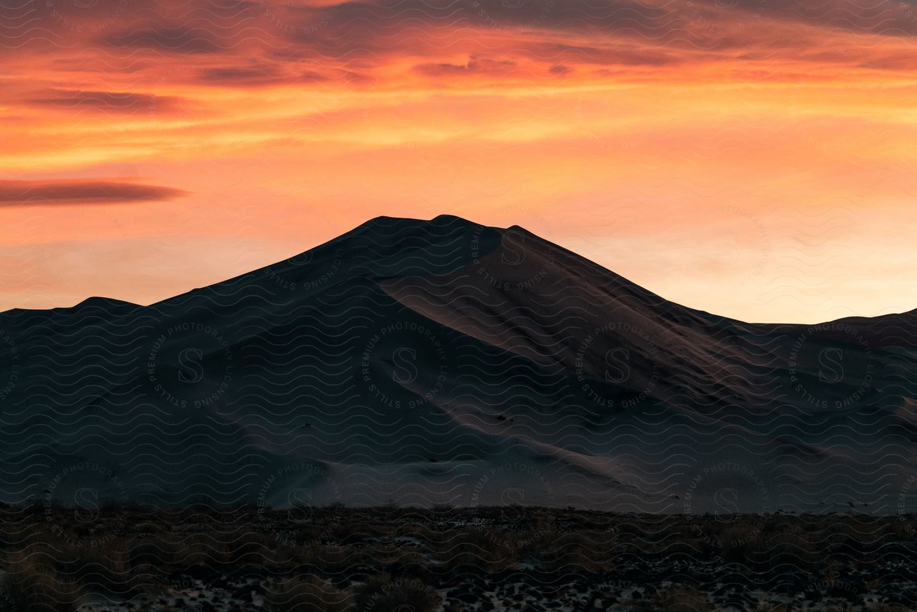A sand dune rises under a red sky