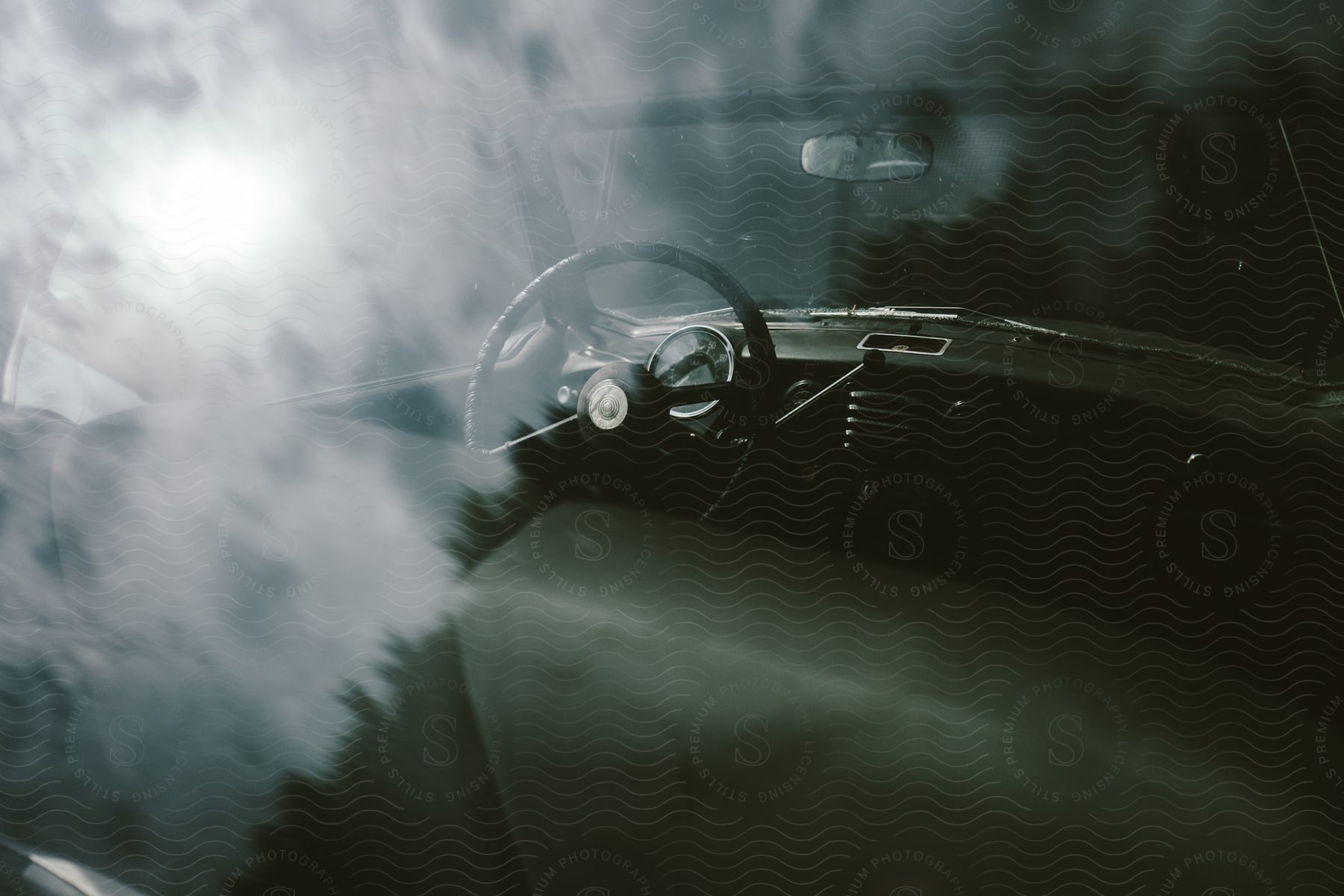 Rear seats of a car with handlebars and window surrounded by smoke