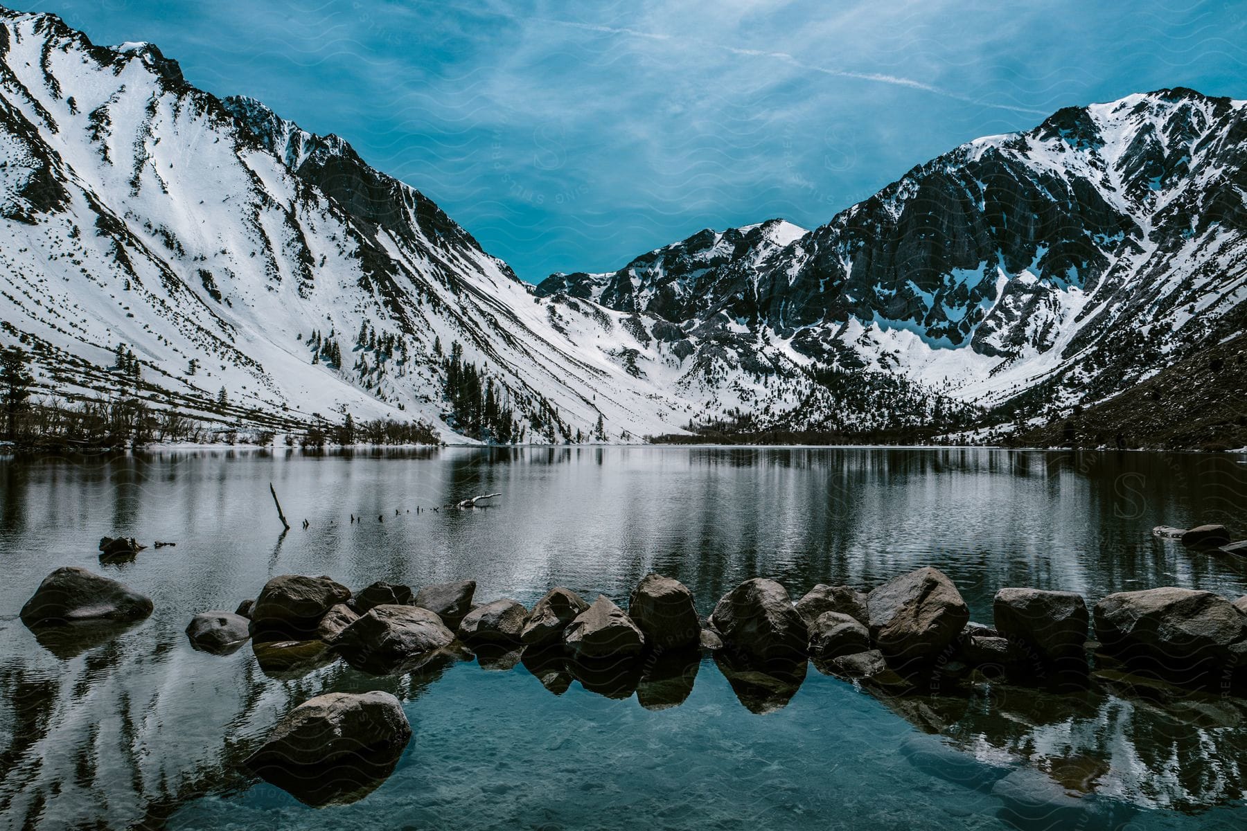 A serene mountain landscape with a lake snowy peaks and a glacier