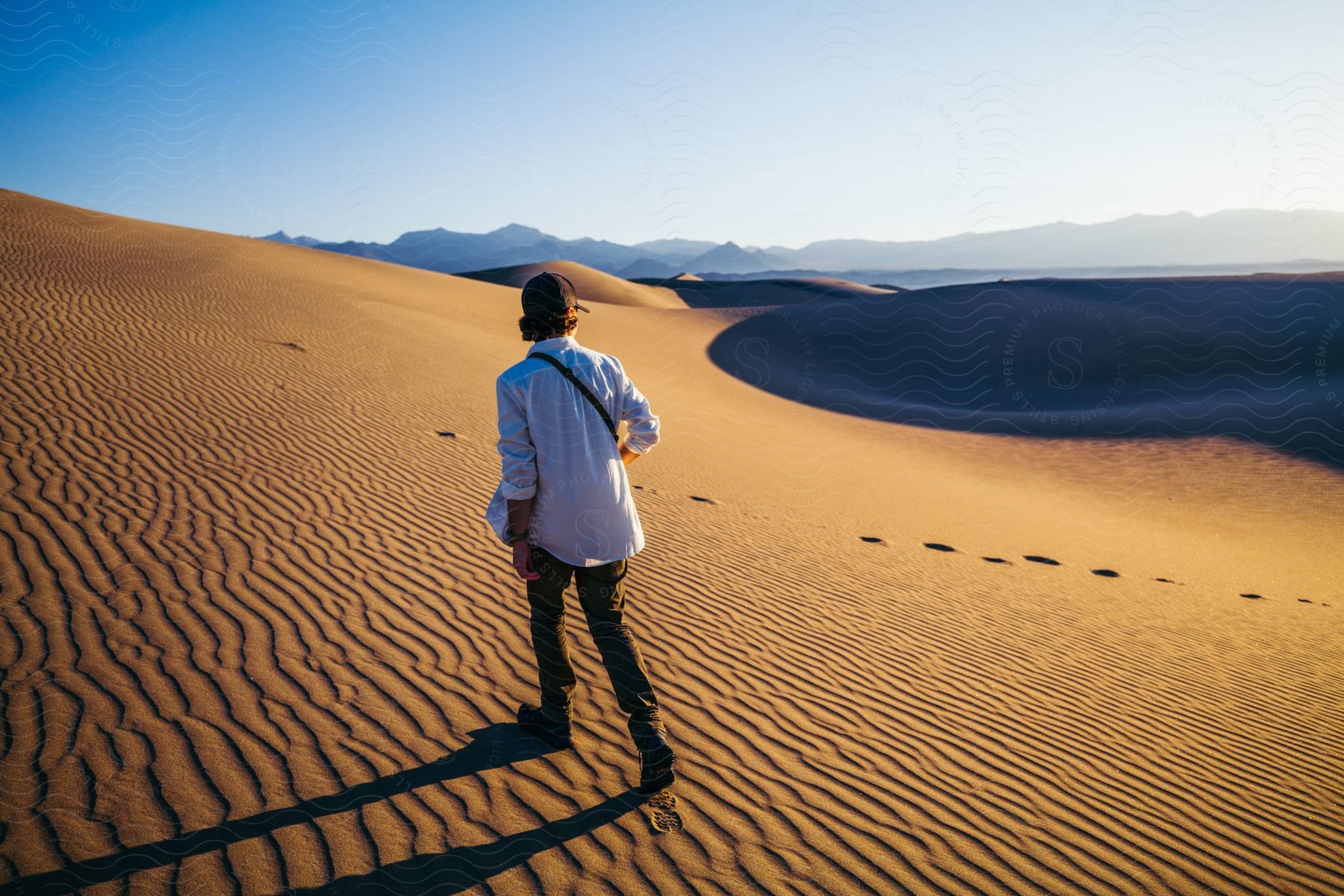 A man walks in desert sand dunes on a sunny day