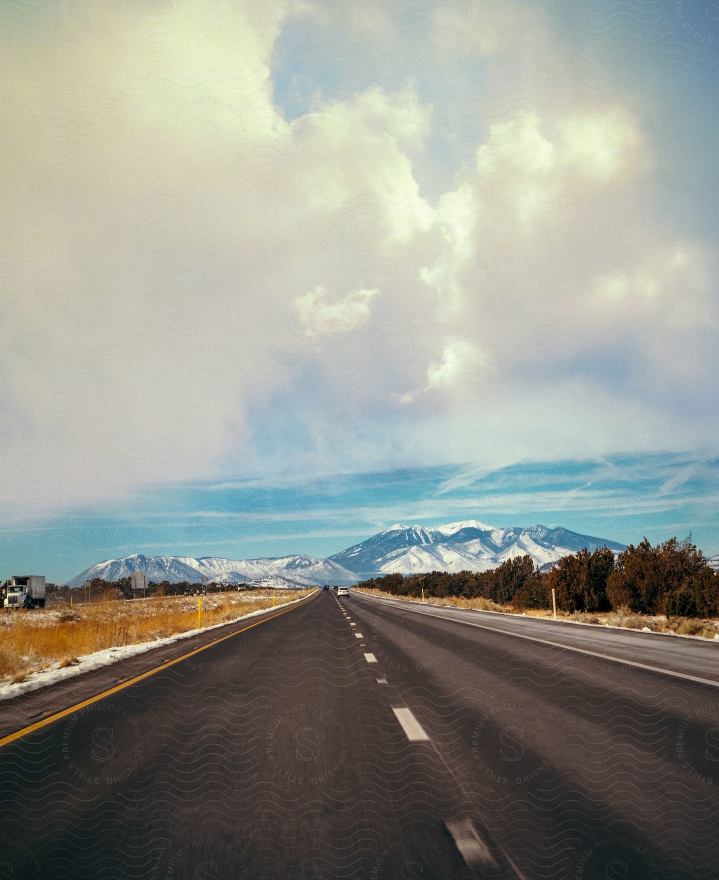 Highway stretching into the horizon with snowy mountains captured on a cloudy day