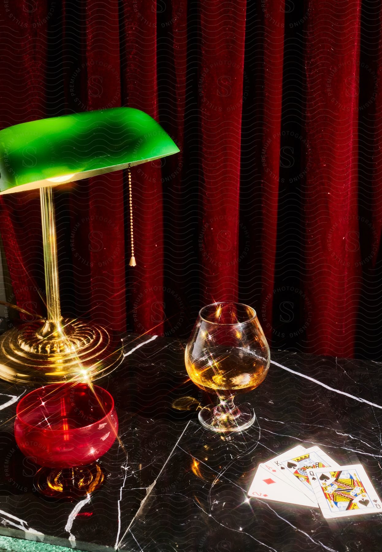 Stock photo of glassware and beverages on a black marble table with a green lamp