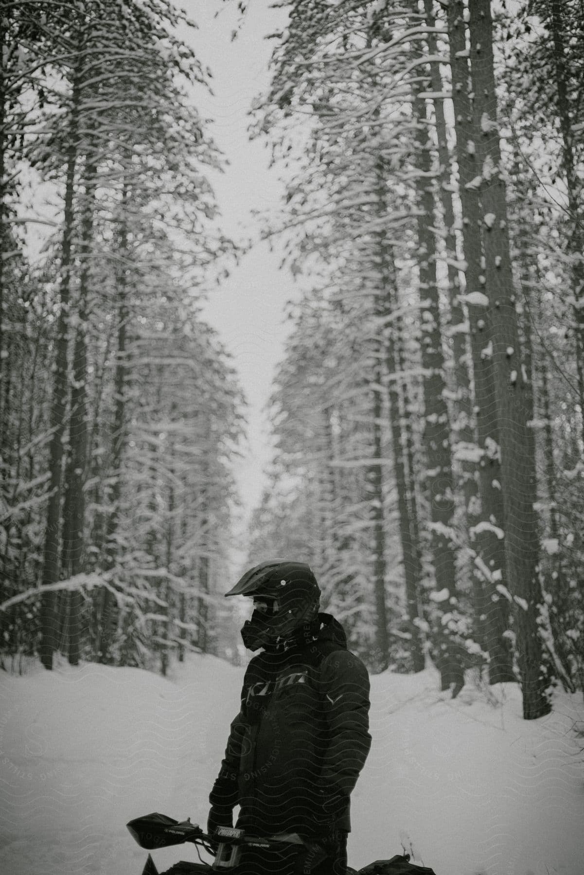 A man stands next to his motorcycle on a snowcovered forest road