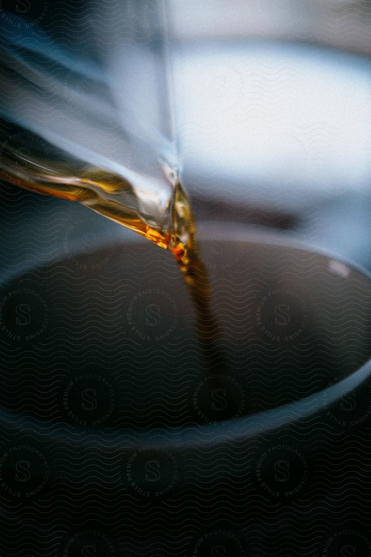 Stock photo of a cup is being filled with a golden brown fluid