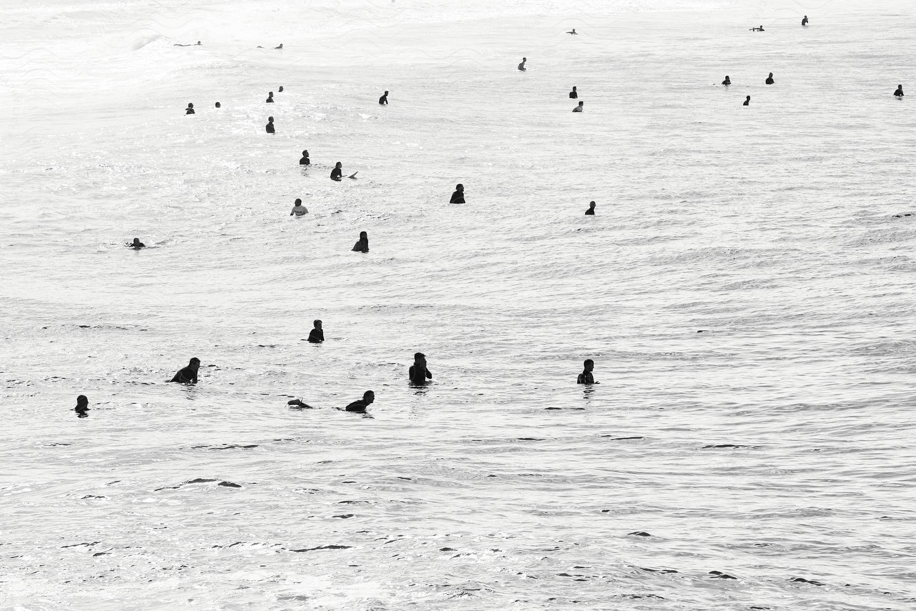 Stock photo of people swimming in the ocean under bright sun creating silhouettes