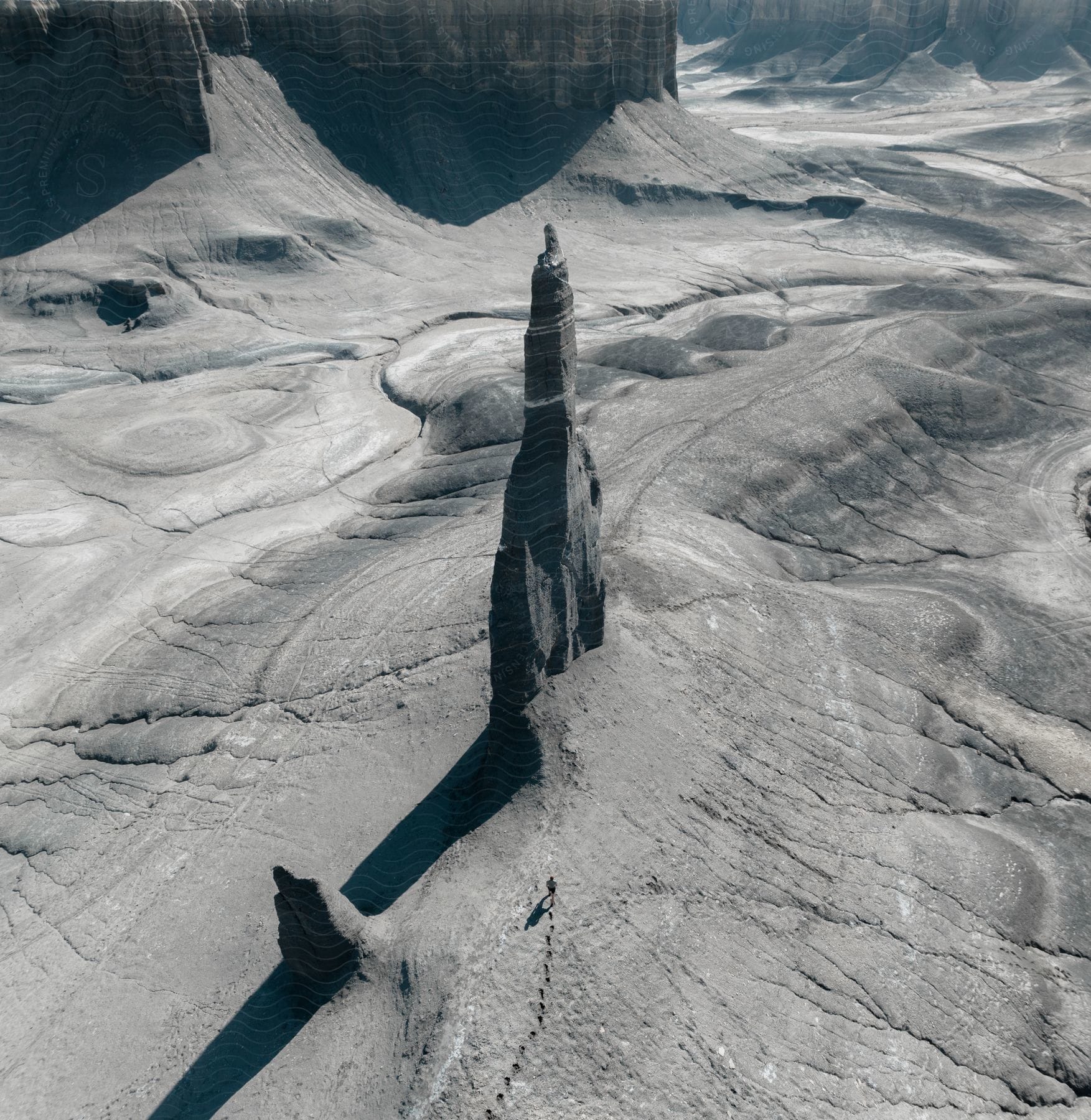 A man walking alone in a barren rocky canyon during the daytime