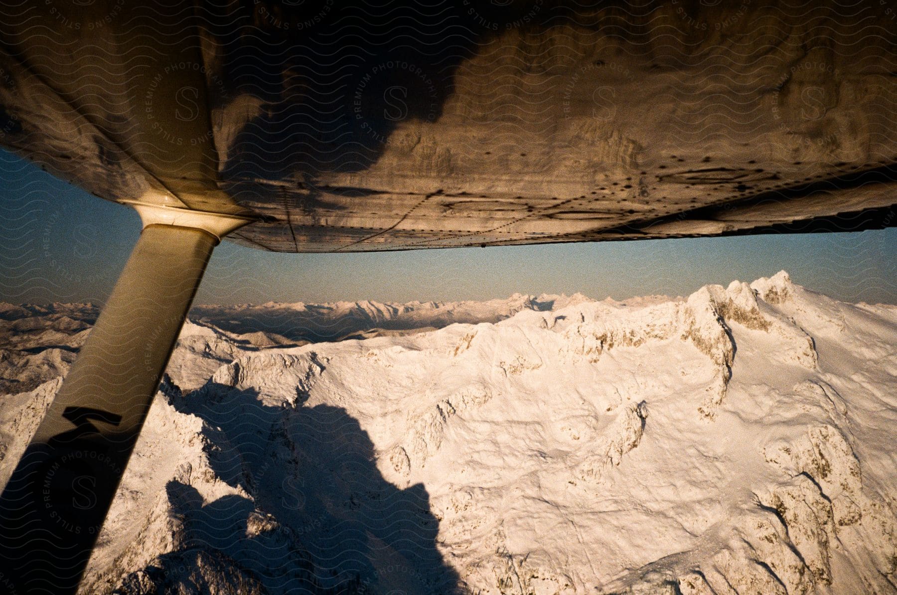 An airplane flies over a snowcovered mountain range