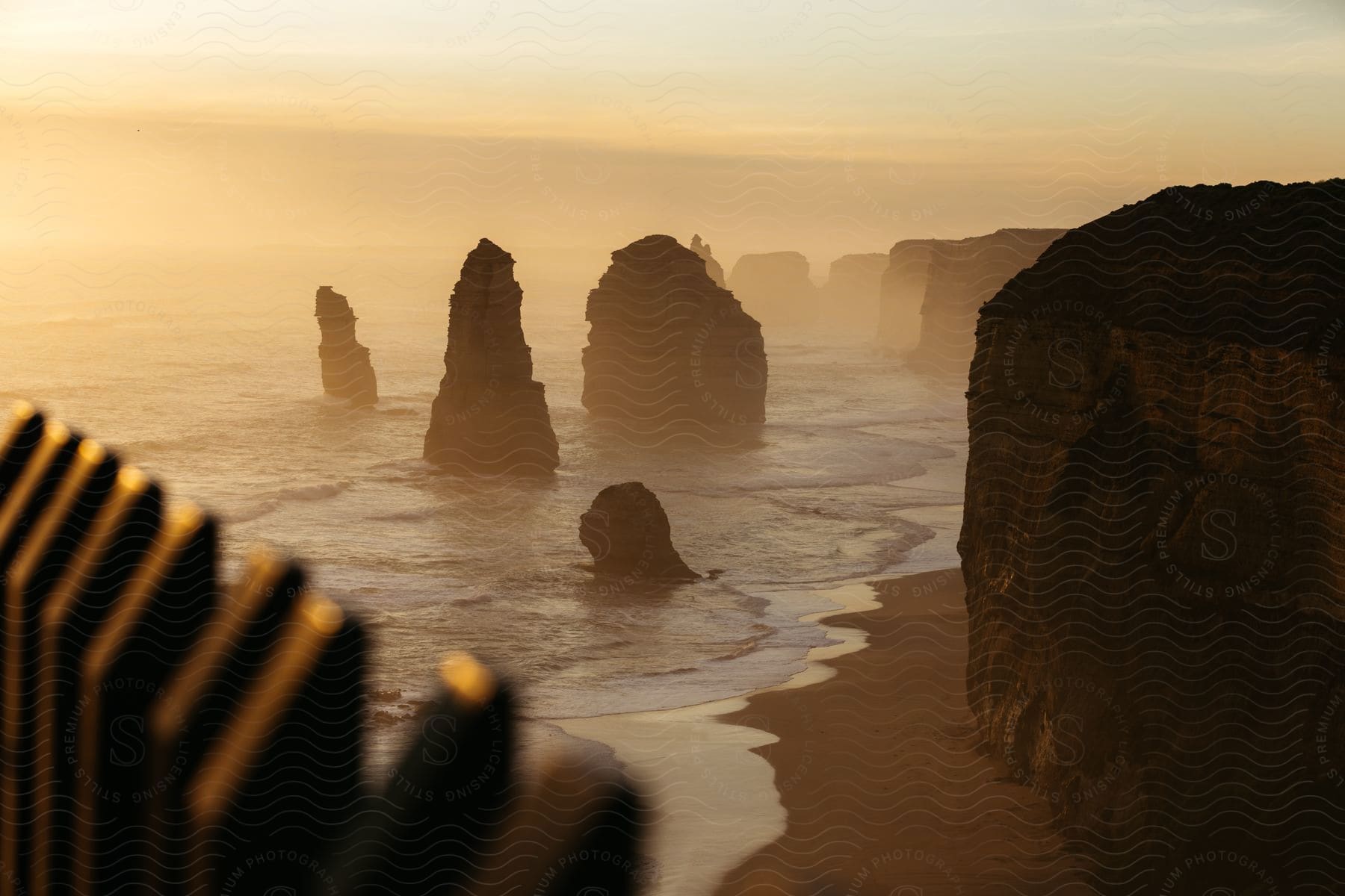 A shoreline with rock formations at dawn with fog