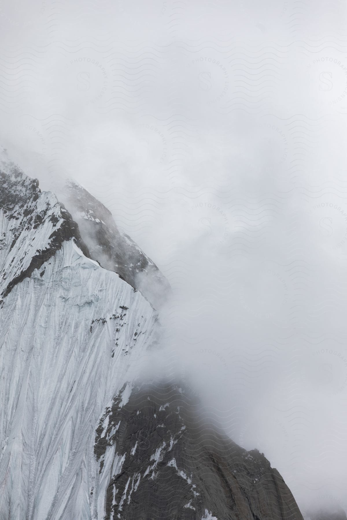 A snowy mountain cliff surrounded by clouds in the karakoram mountain range in pakistan