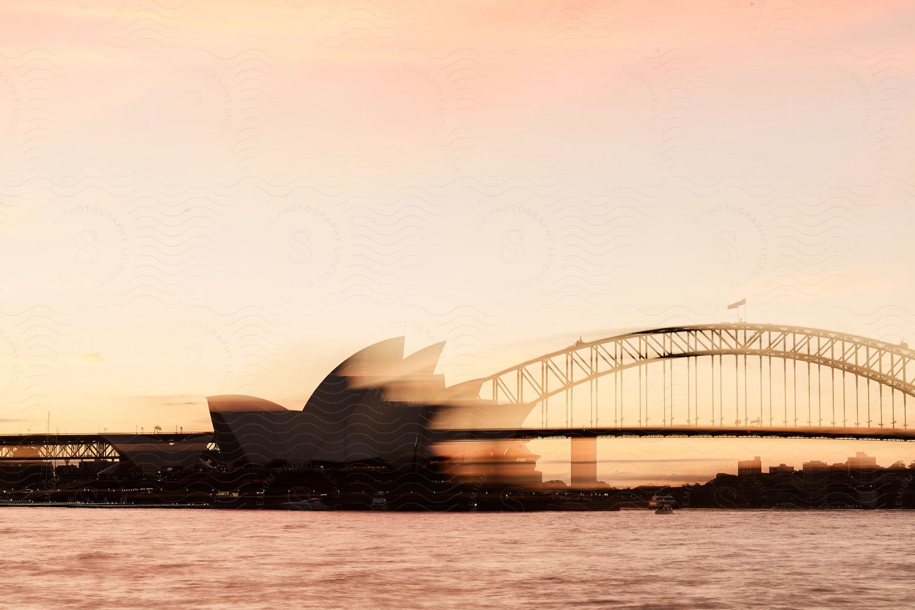 A bridge on water with the sun setting in the horizon